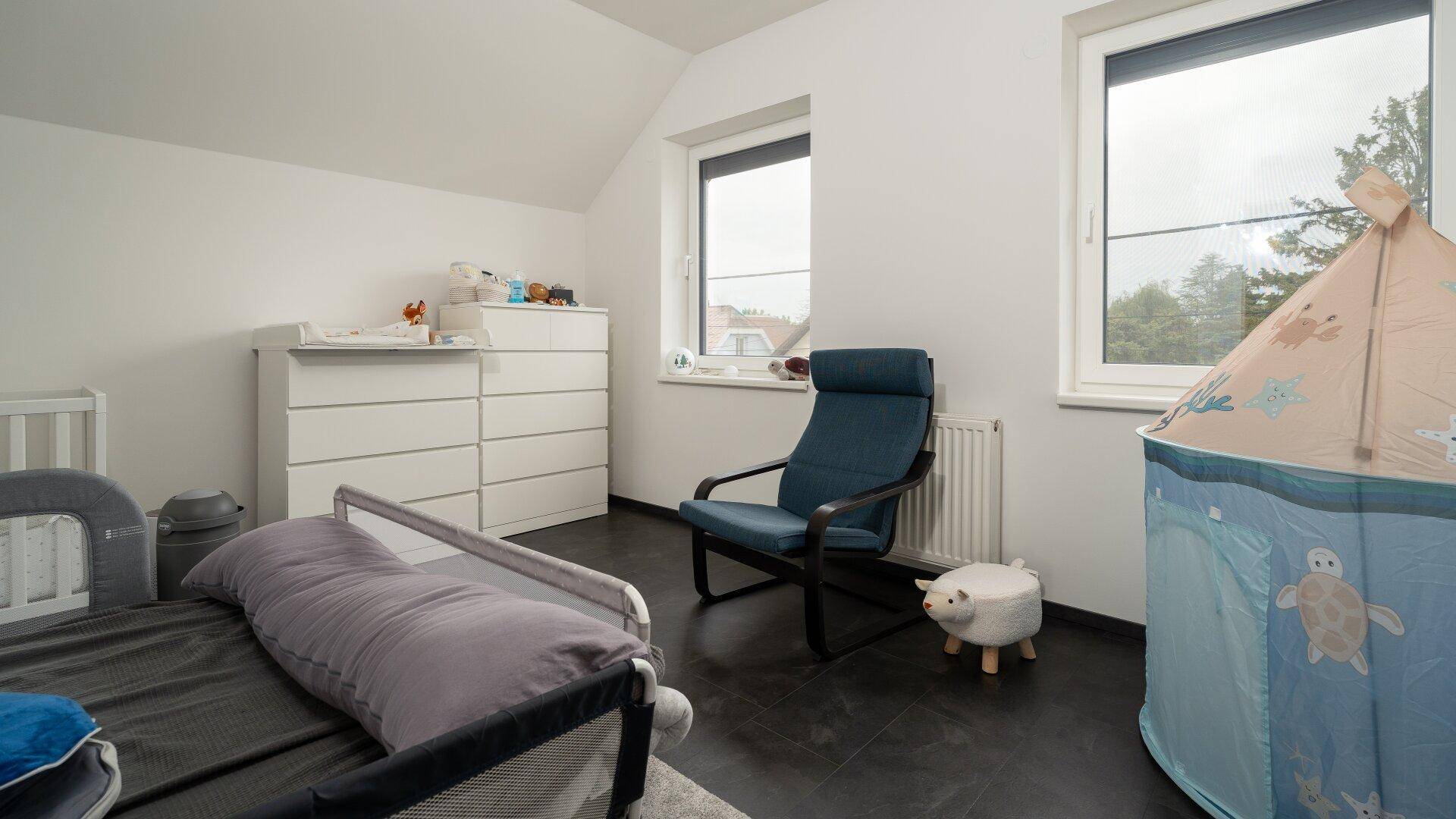 Kinderzimmer mit Wickelkommode, Spielzelt und zwei Fenstern für viel Tageslicht.