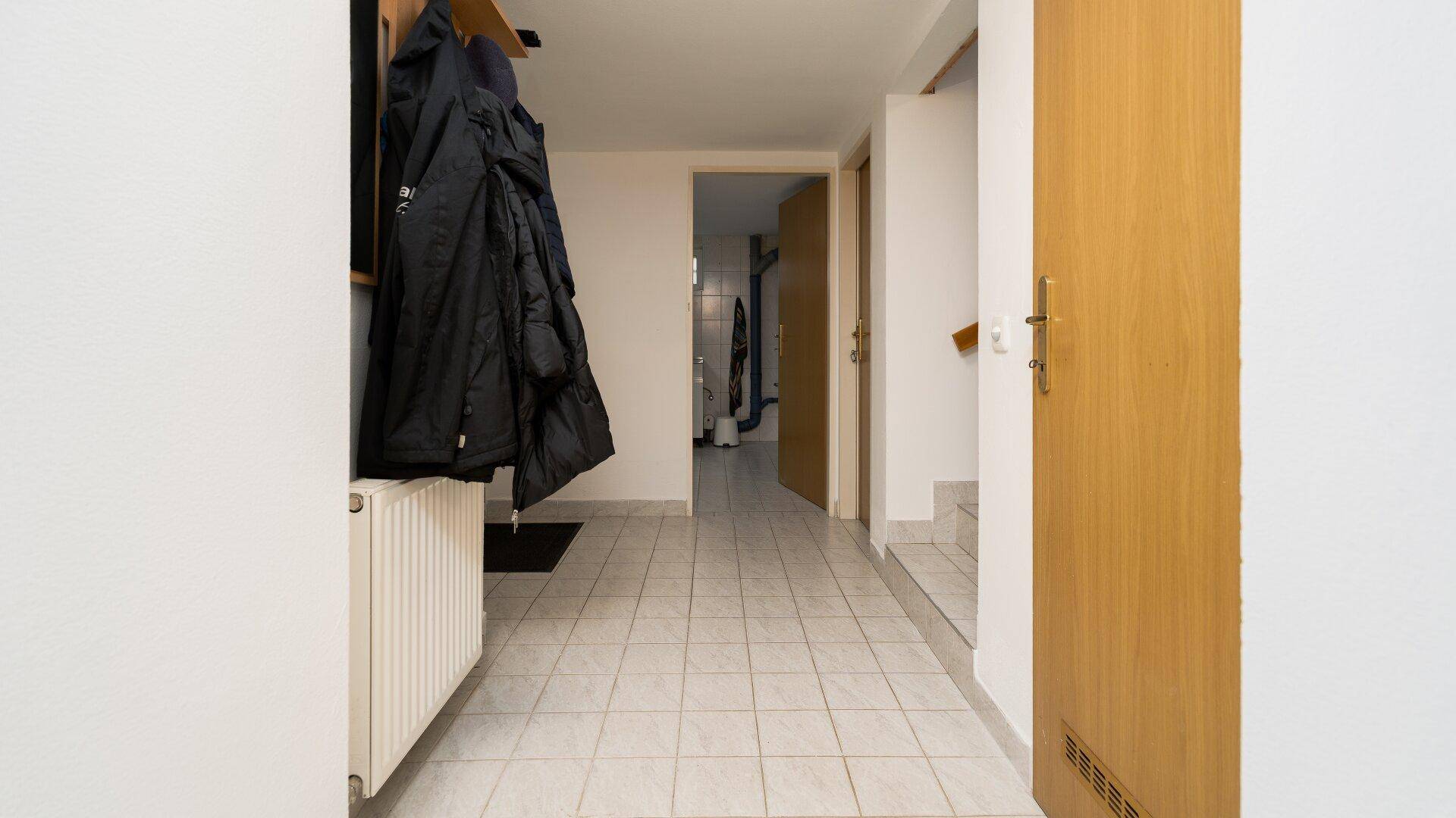 Heller Flur im Untergeschoss mit Fliesenboden und Zugang zu verschiedenen Räumen.