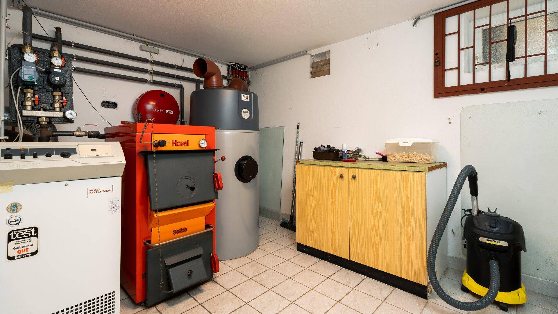 Heizungsraum im Keller mit großen Heizungsanlagen und gefliestem Boden.