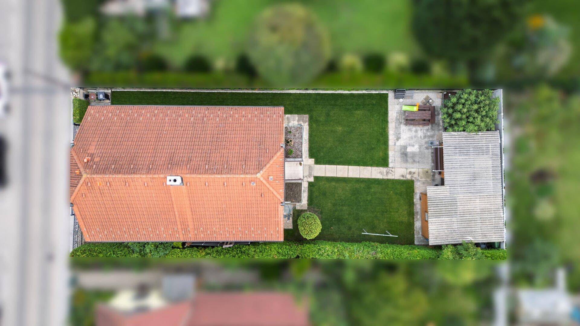 Luftaufnahme des Grundstücks mit Wohnhaus, gepflegtem Garten und Gartenhaus.