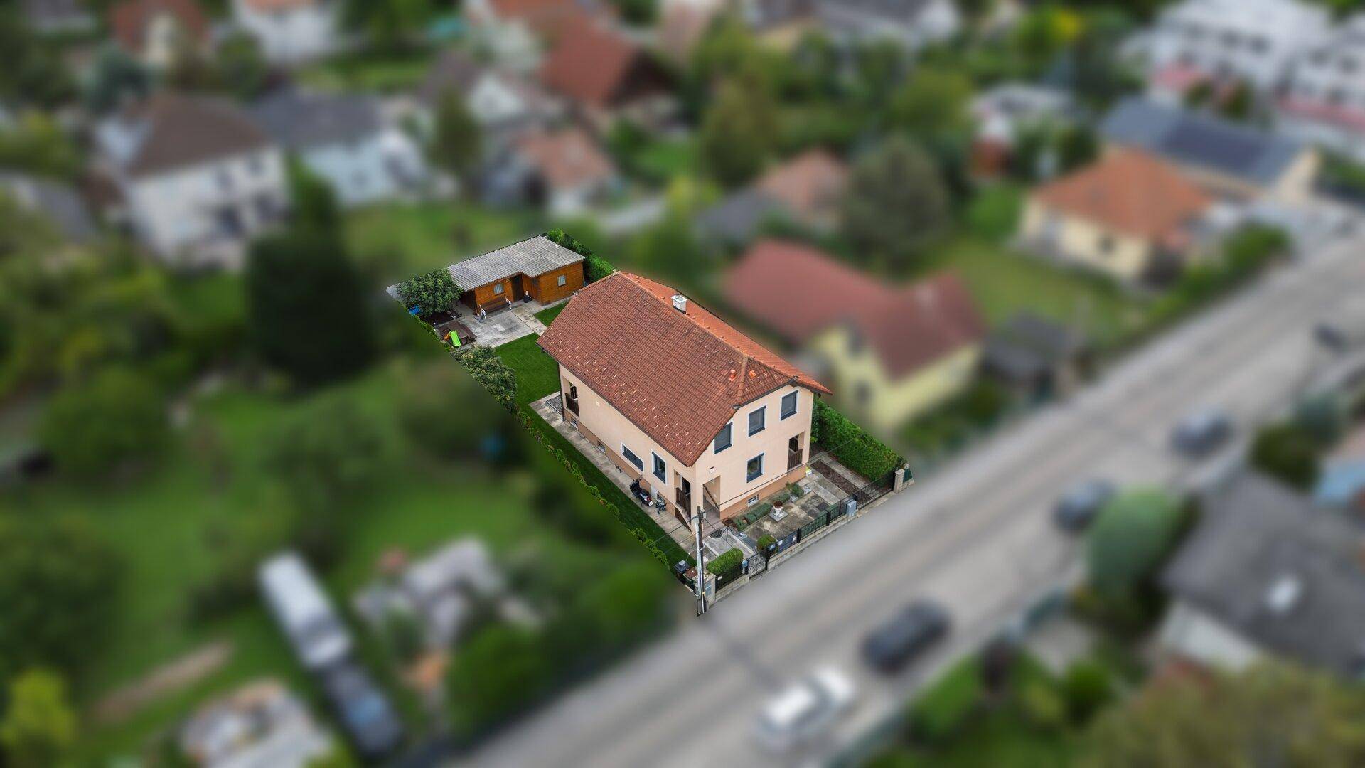 Übersichtliche Luftaufnahme des Anwesens mit Wohnhaus, Garten und angrenzender Straße.