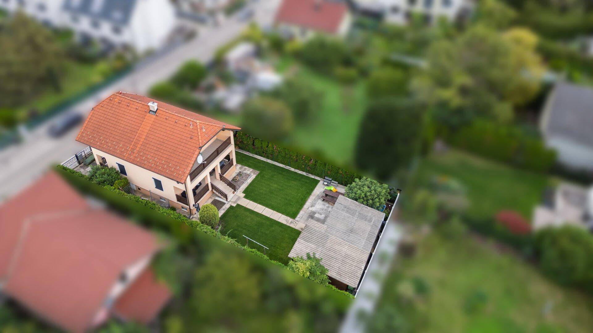 Luftaufnahme der Rückseite des Hauses mit Balkonen, Garten und dem Gartenhaus.
