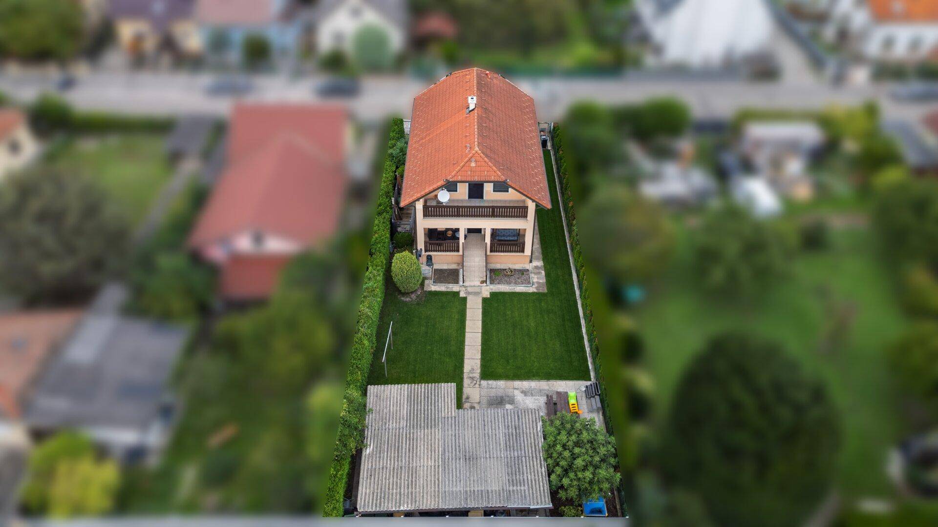 Luftaufnahme der Vorderseite des Hauses mit gepflegtem Garten und dem Gartenhaus.