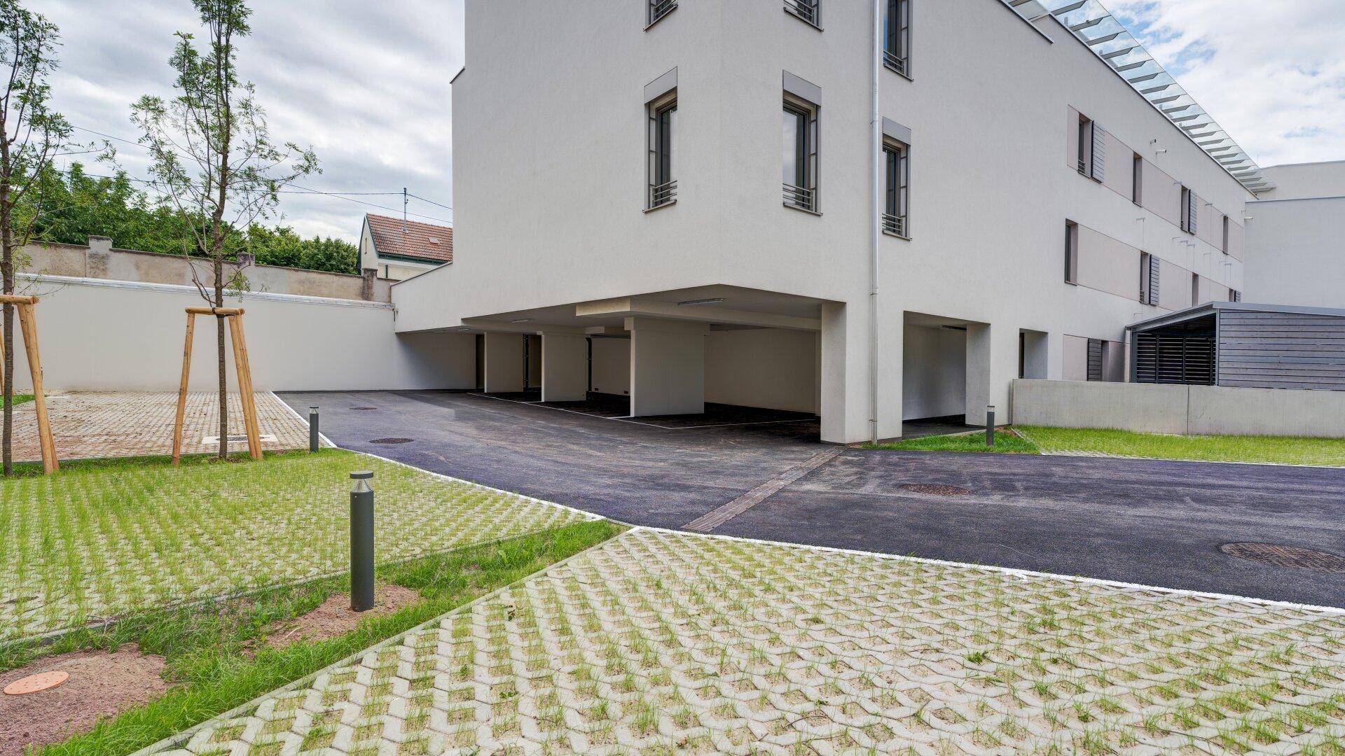 Ansicht der modernen Wohnanlage mit überdachten Parkplätzen und begrünten Außenbereichen.
