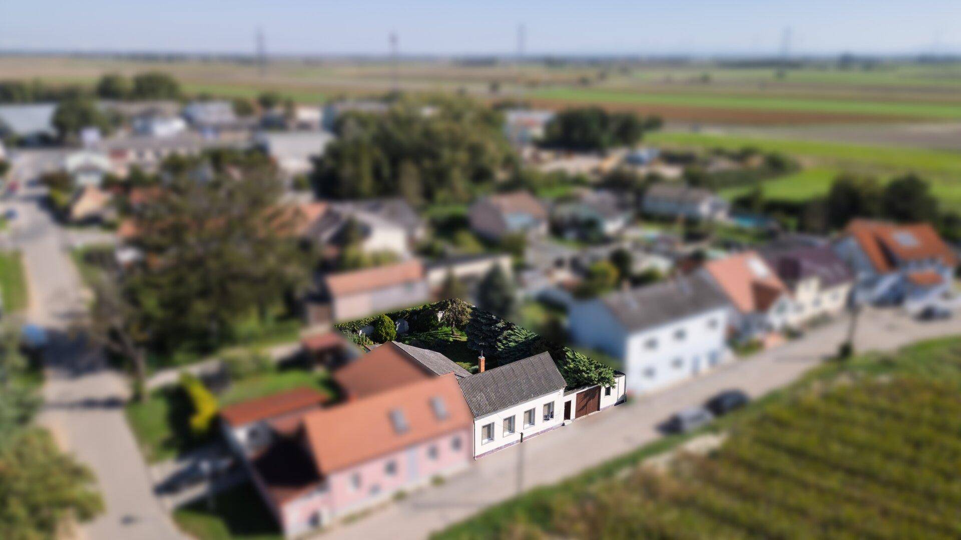 Weitläufige Luftaufnahme des Hauses in ländlicher Umgebung mit Feldern im Hintergrund.