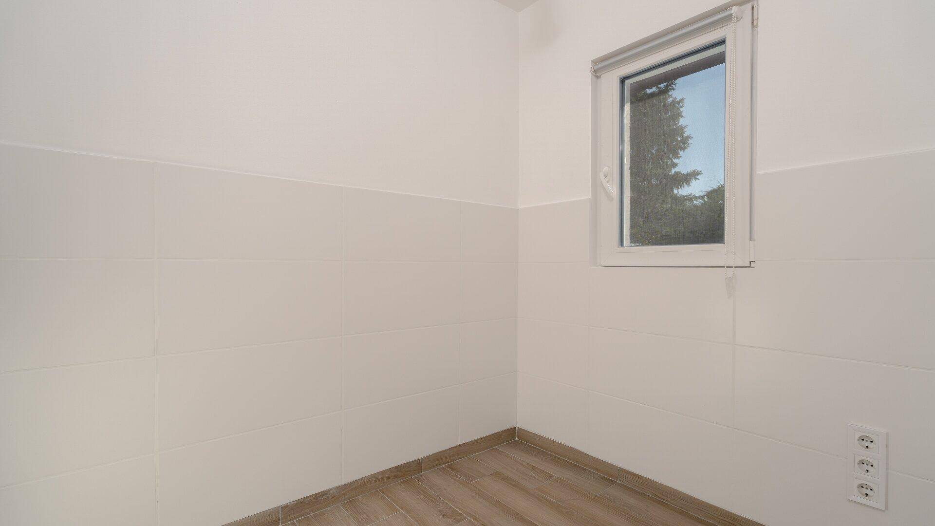 Kleiner, hell gefliester Raum mit Fenster und Steckdosen, ideal als separates WC.