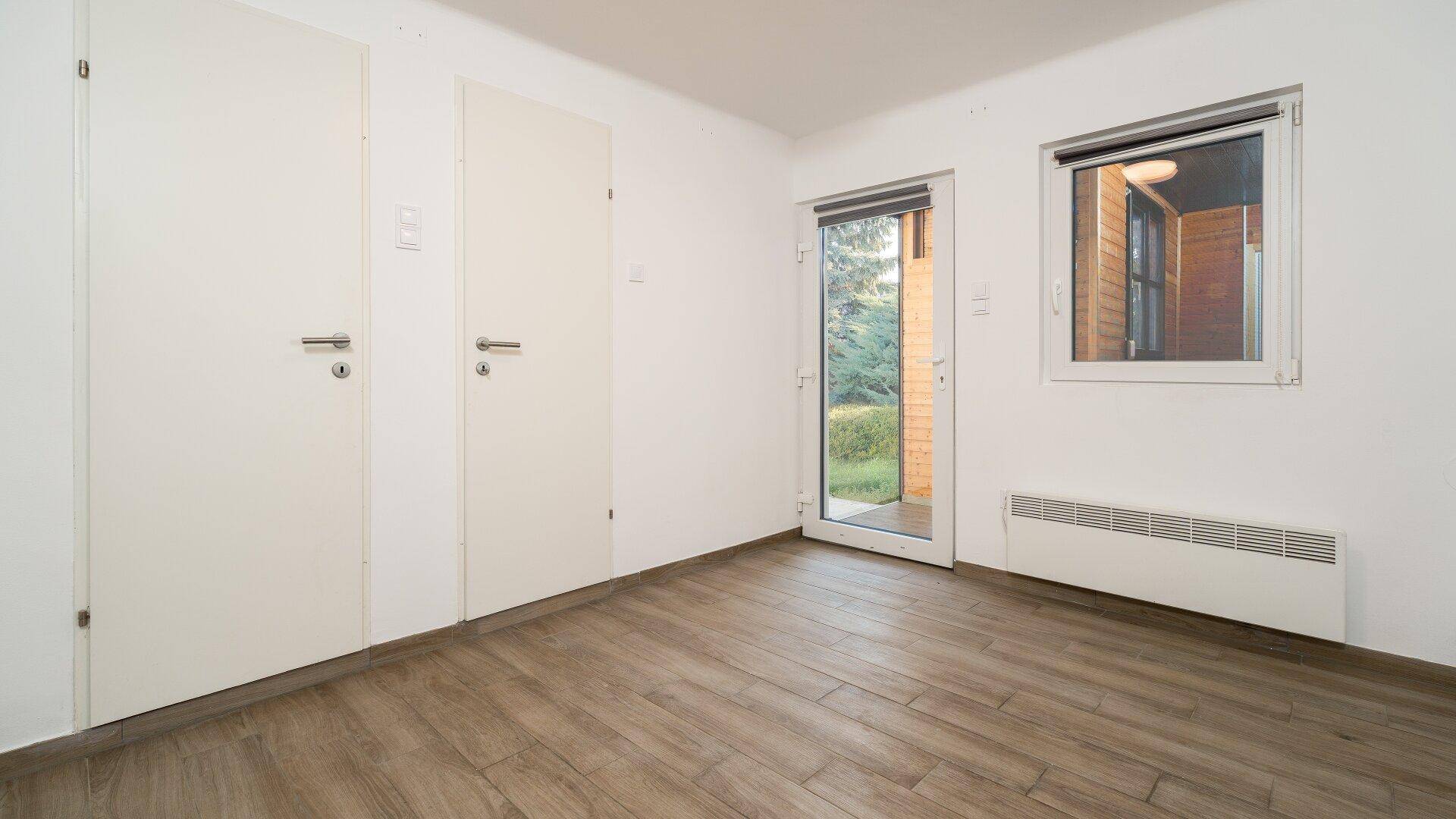Raum mit praktischen Einbauschränken, Laminatboden und direktem Zugang zum Garten.
