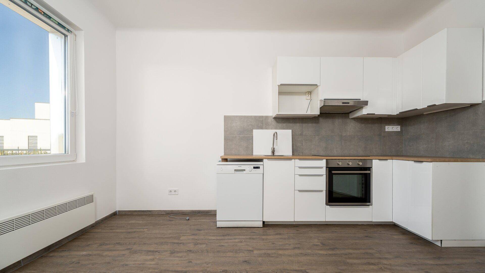 Funktionale Küche mit weißen Unterschränken, Holz-Arbeitsplatte und großem Fenster.