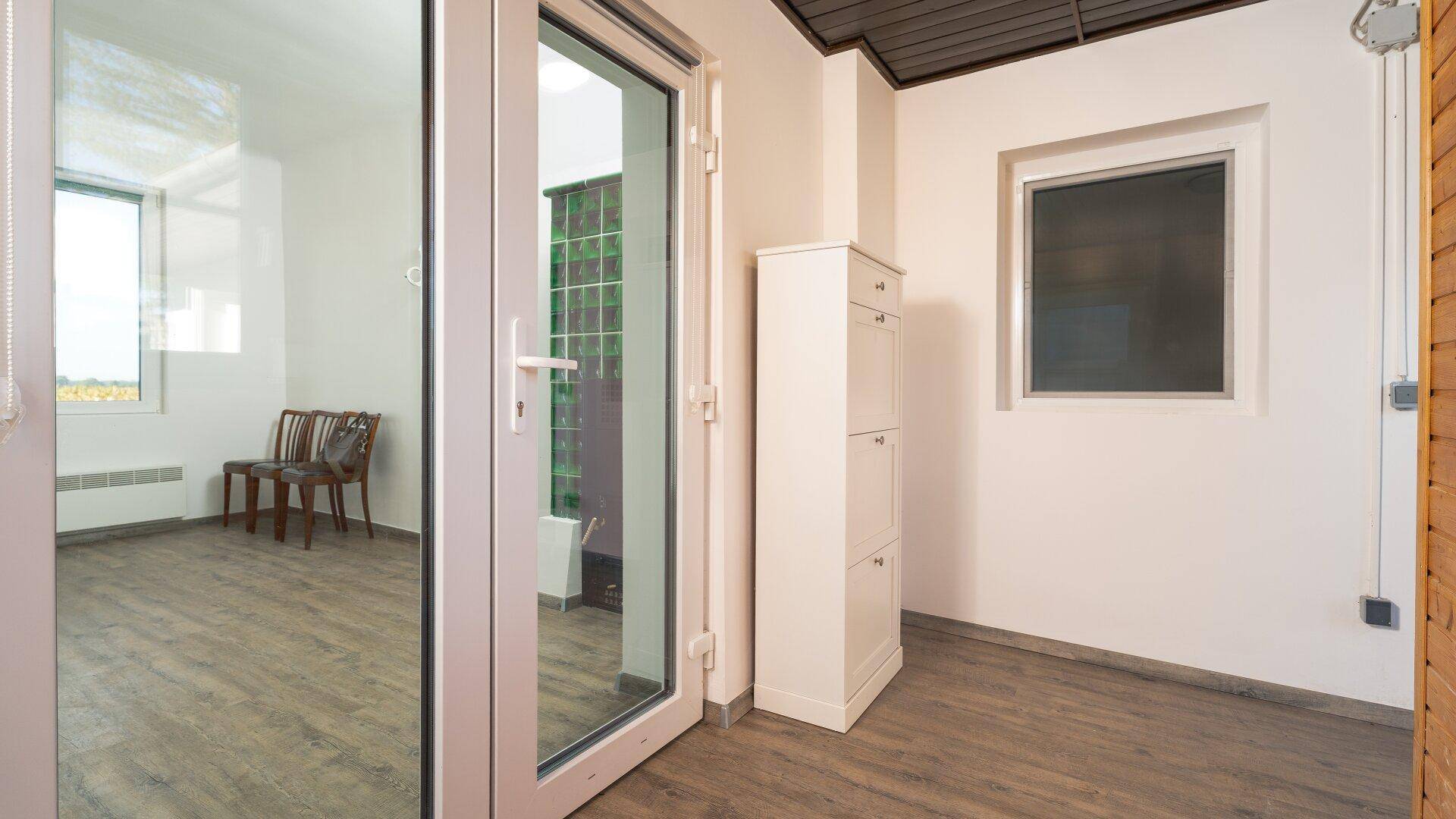Heller Eingangsbereich mit modernem Laminatboden und Blick in einen weiteren Raum.