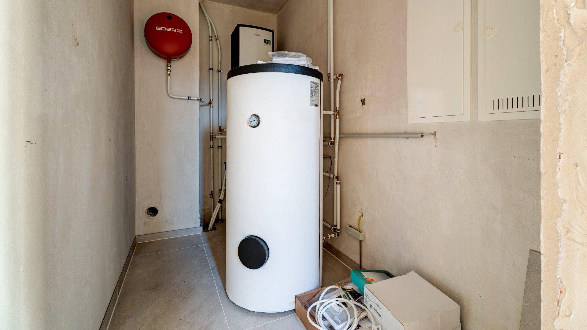 Technikraum mit Warmwasserspeicher und sichtbaren Installationen, funktional und praktisch.