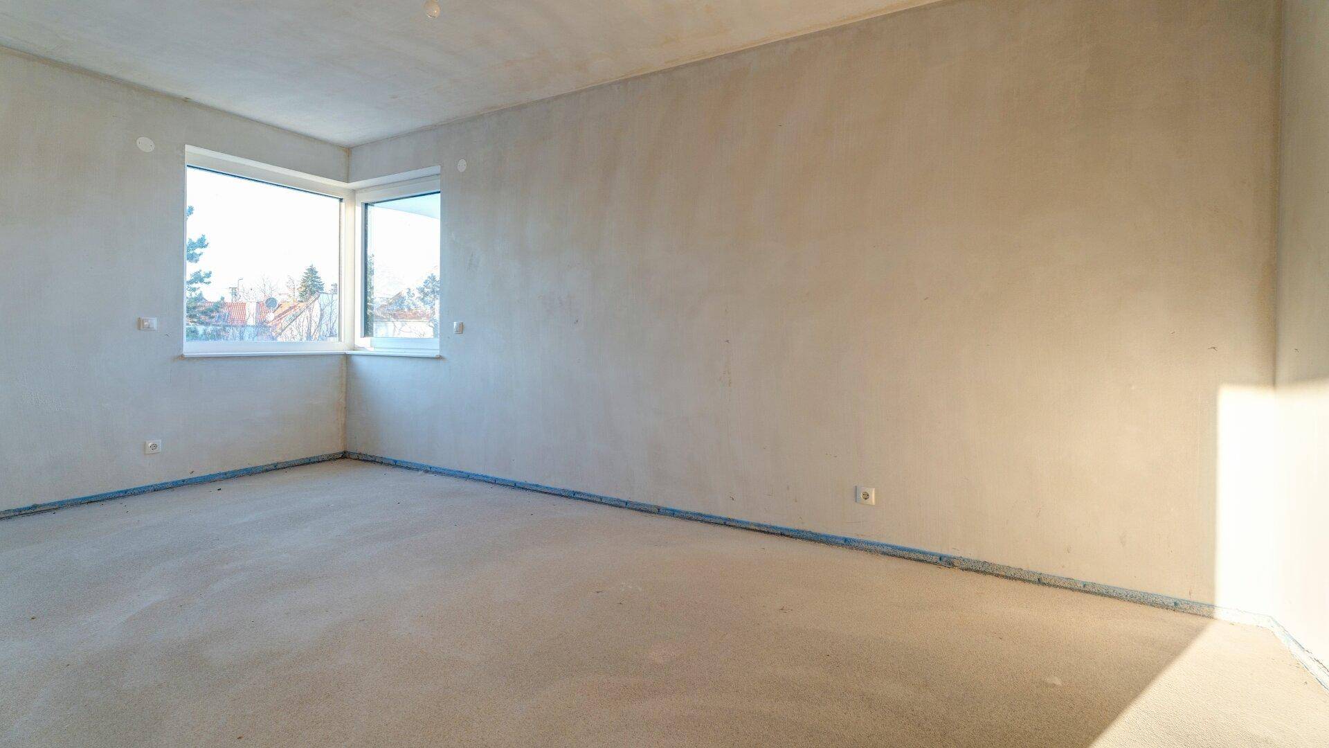 Heller, unfertiger Raum mit Eckfenstern, bietet viel Tageslicht und Ausblick.