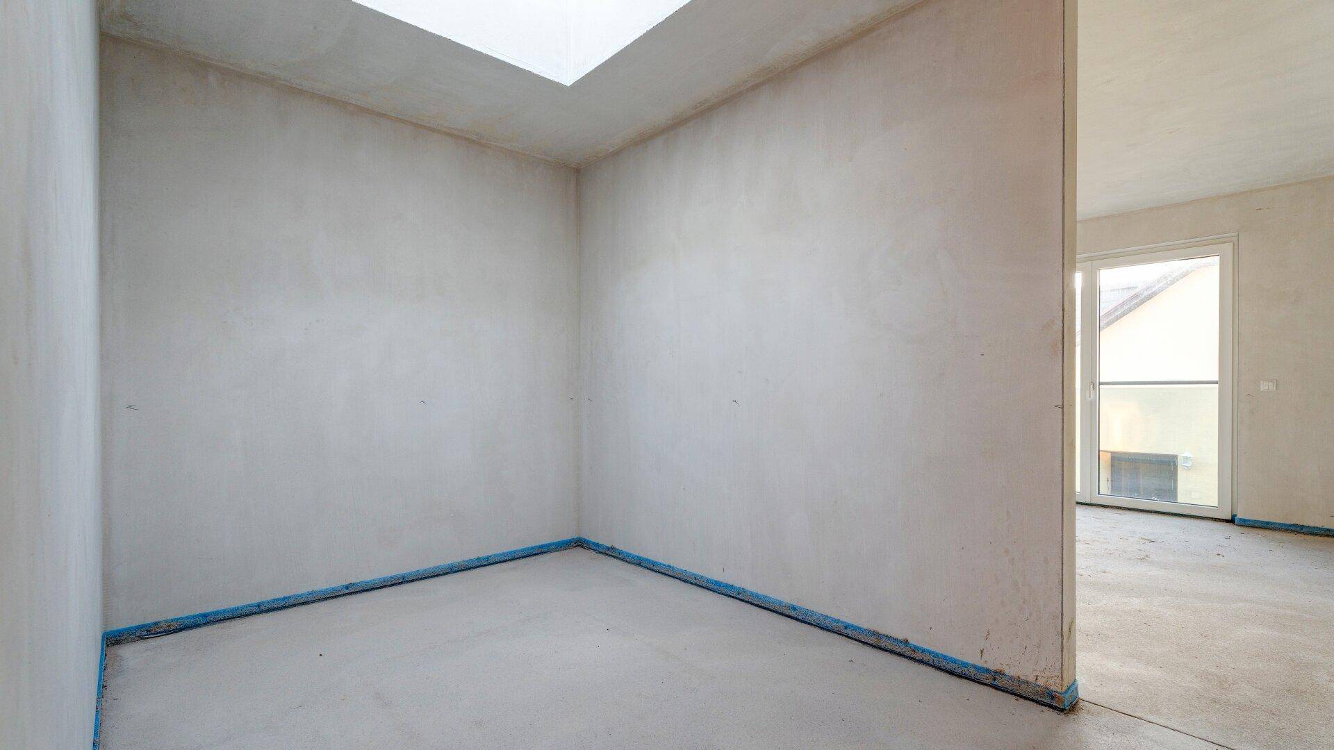 Unfertiger Raum mit Oberlicht, bietet natürliches Licht von oben, bereit für den Ausbau.