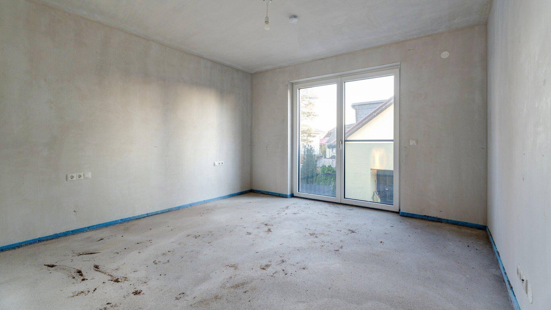 Unfertiger Raum mit großer Schiebetür zum Außenbereich, bietet viel Tageslicht.