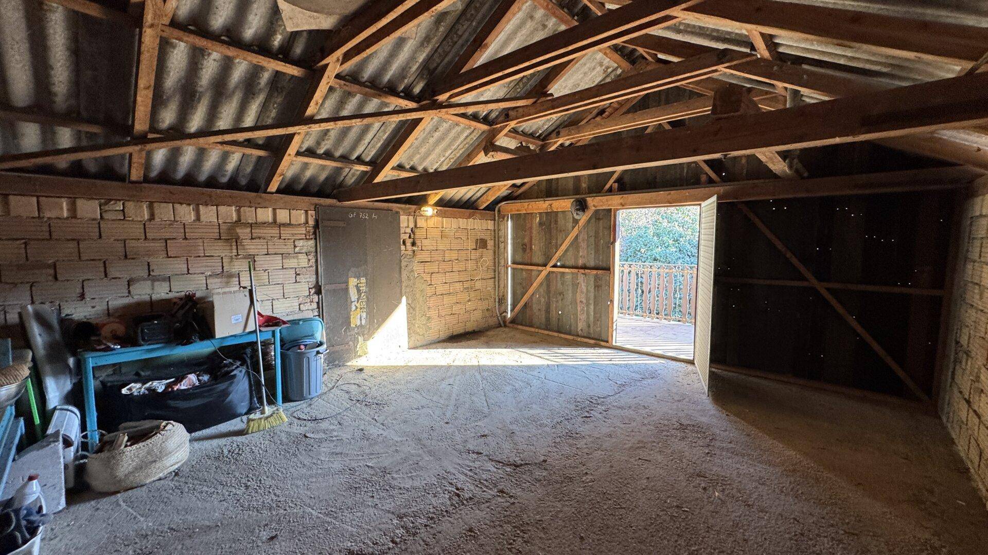 Großer, unfertiger Dachboden mit sichtbaren Holzbalken und viel Tageslicht.