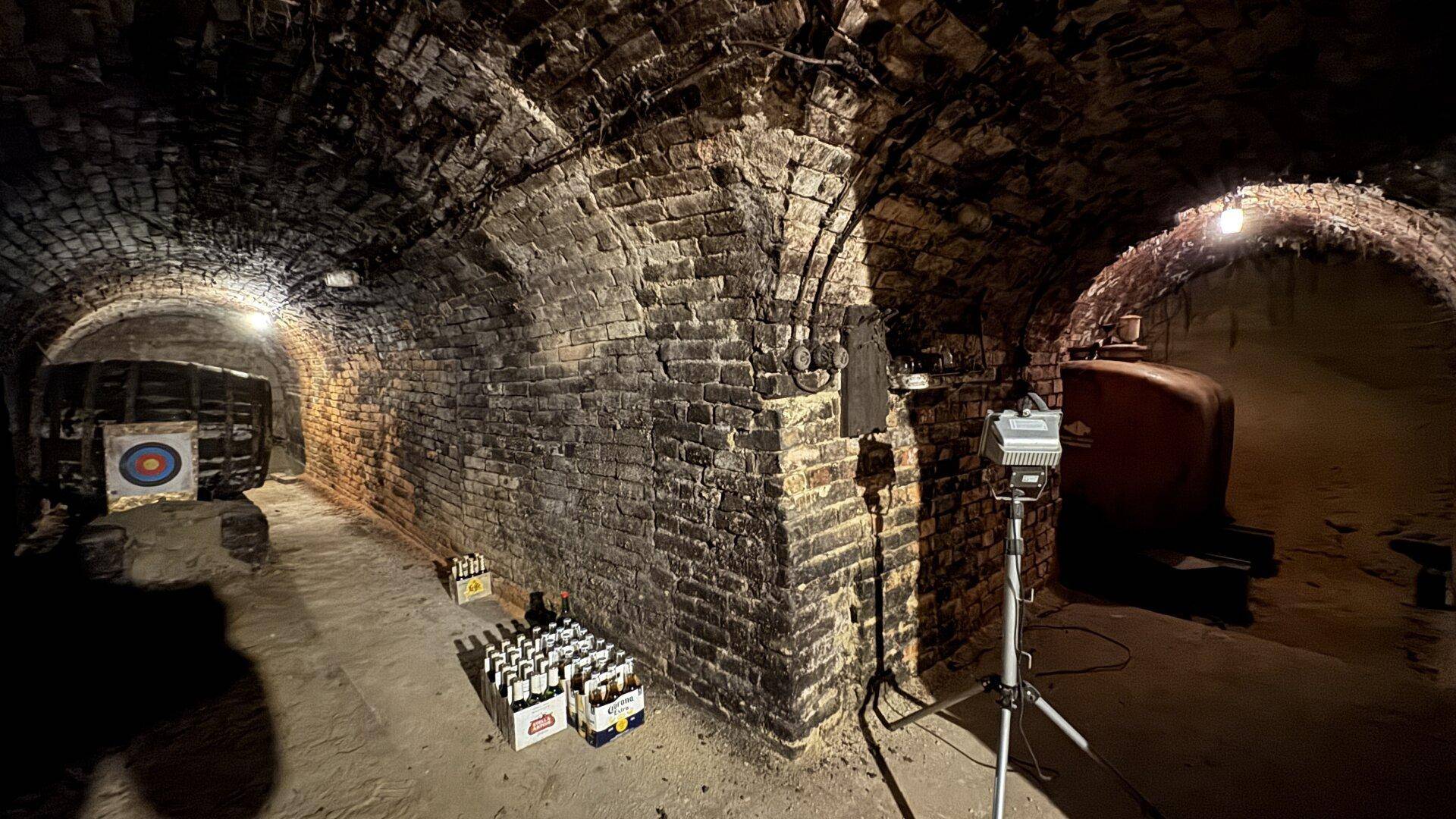 Dunkler Gewölbekeller mit Ziegelmauerwerk und historischem Ambiente, ideal für Weinlagerung.