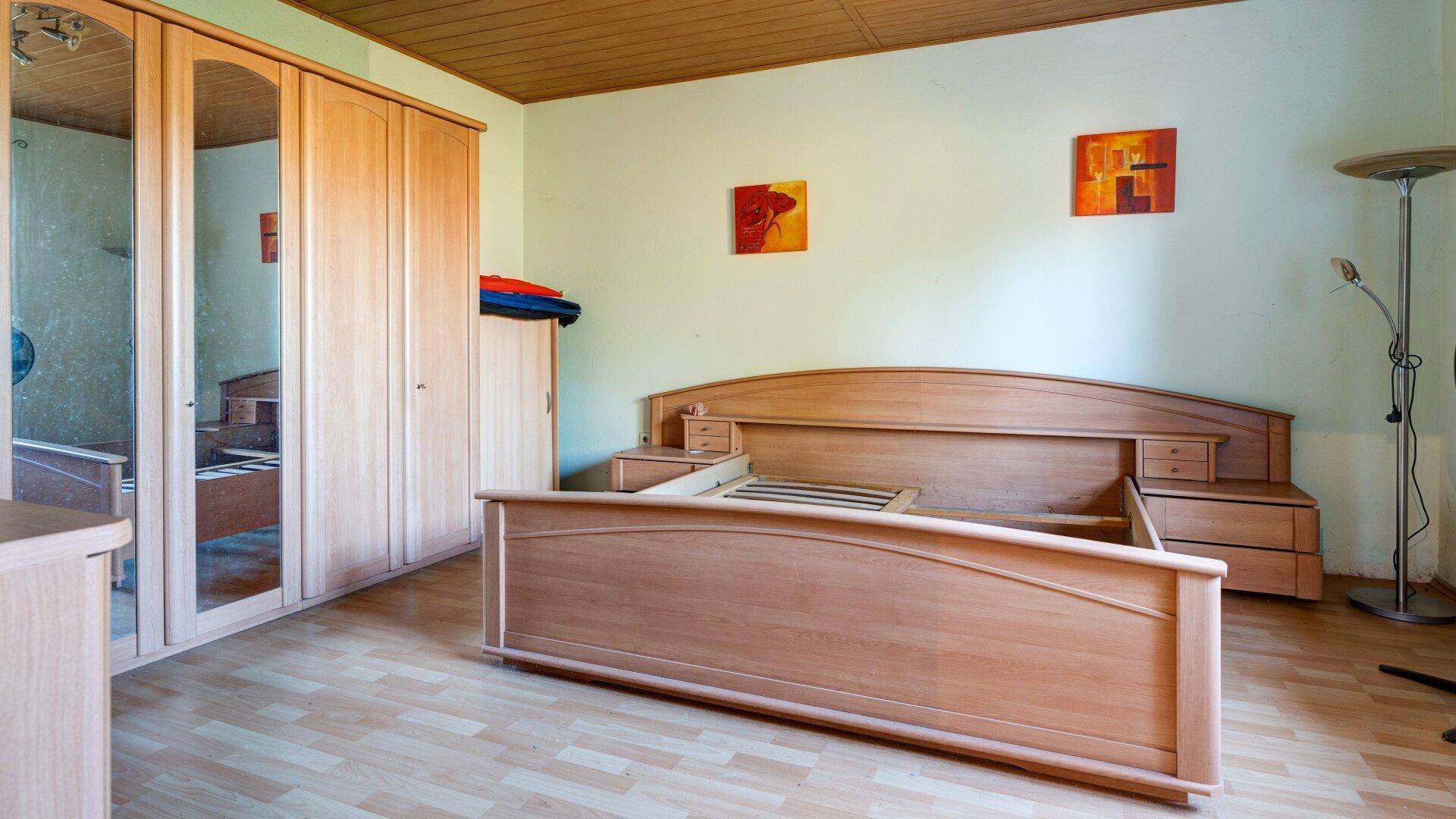 Schlafzimmer mit einem Holzdoppelbett und einem großen Kleiderschrank mit Spiegeltüren.