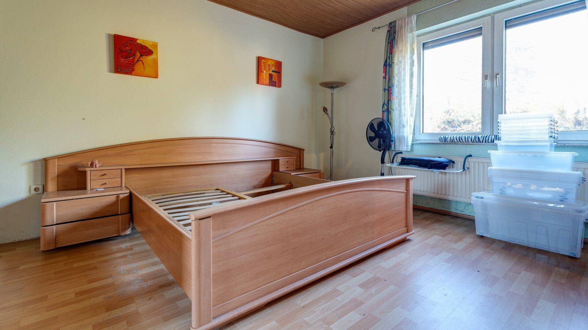 Schlafzimmer mit einem Holzdoppelbett und einem Fenster, das den Raum mit Tageslicht versorgt.