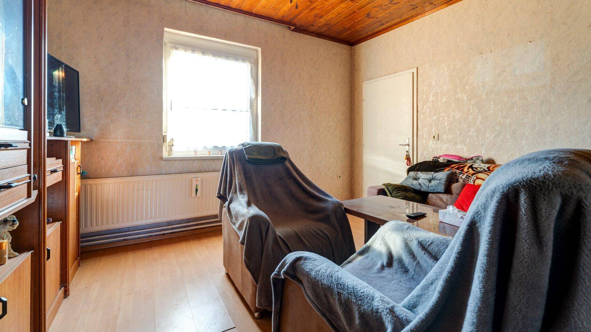 Gemütliches Wohnzimmer mit zwei Sesseln, Fernseher und einem Fenster für natürliches Licht.