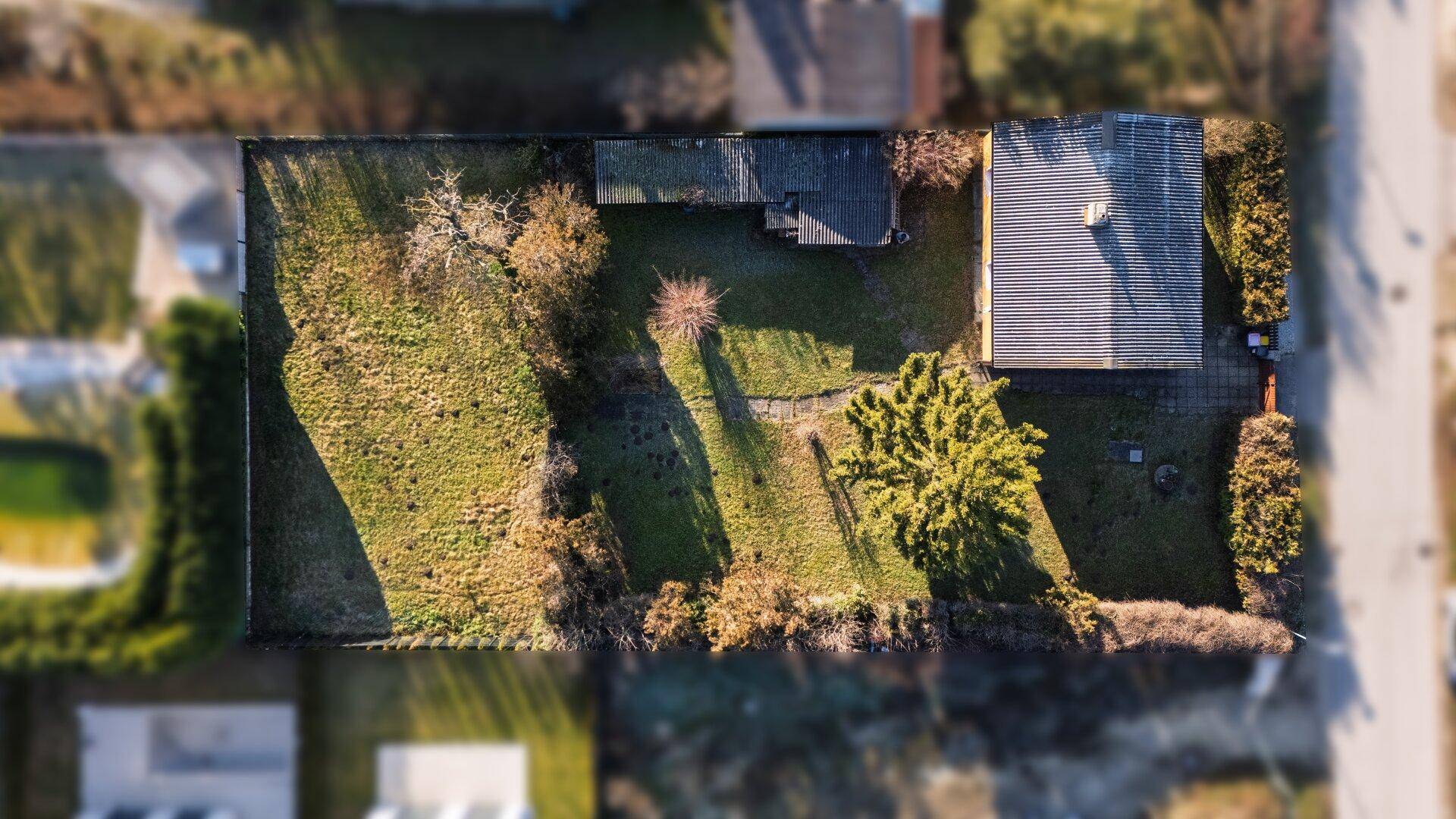 Vogelperspektive des Grundstücks mit Haus, Nebengebäuden und der Gartenanlage.
