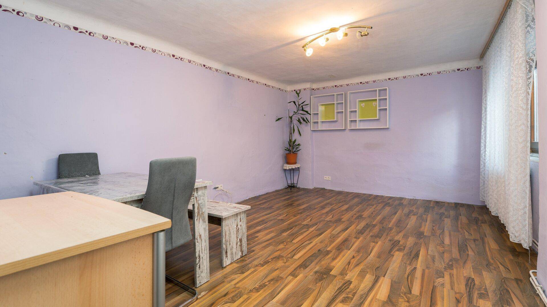 Esszimmer mit lila Wänden, Holzboden und einem Esstisch mit Sitzbank, in einem gemütlichen Ambiente.
