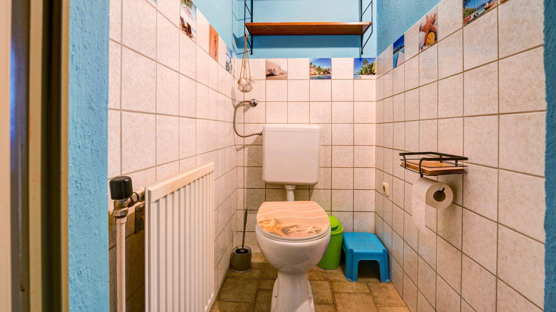 Kleines Gäste-WC mit Fliesen an den Wänden und einem einfachen WC, funktional und hell.