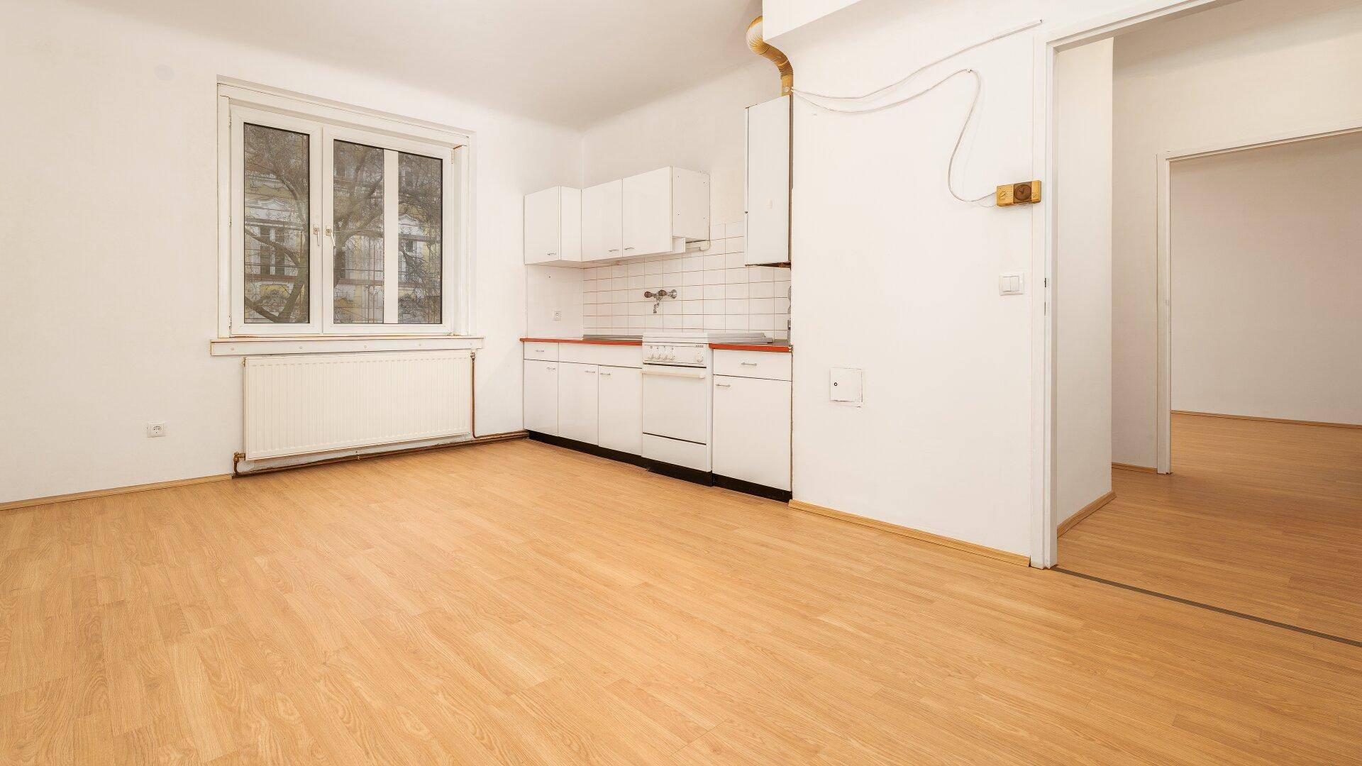 Einfache Küche mit weißen Schränken, Spüle und Herd, bereit für die individuelle Gestaltung.