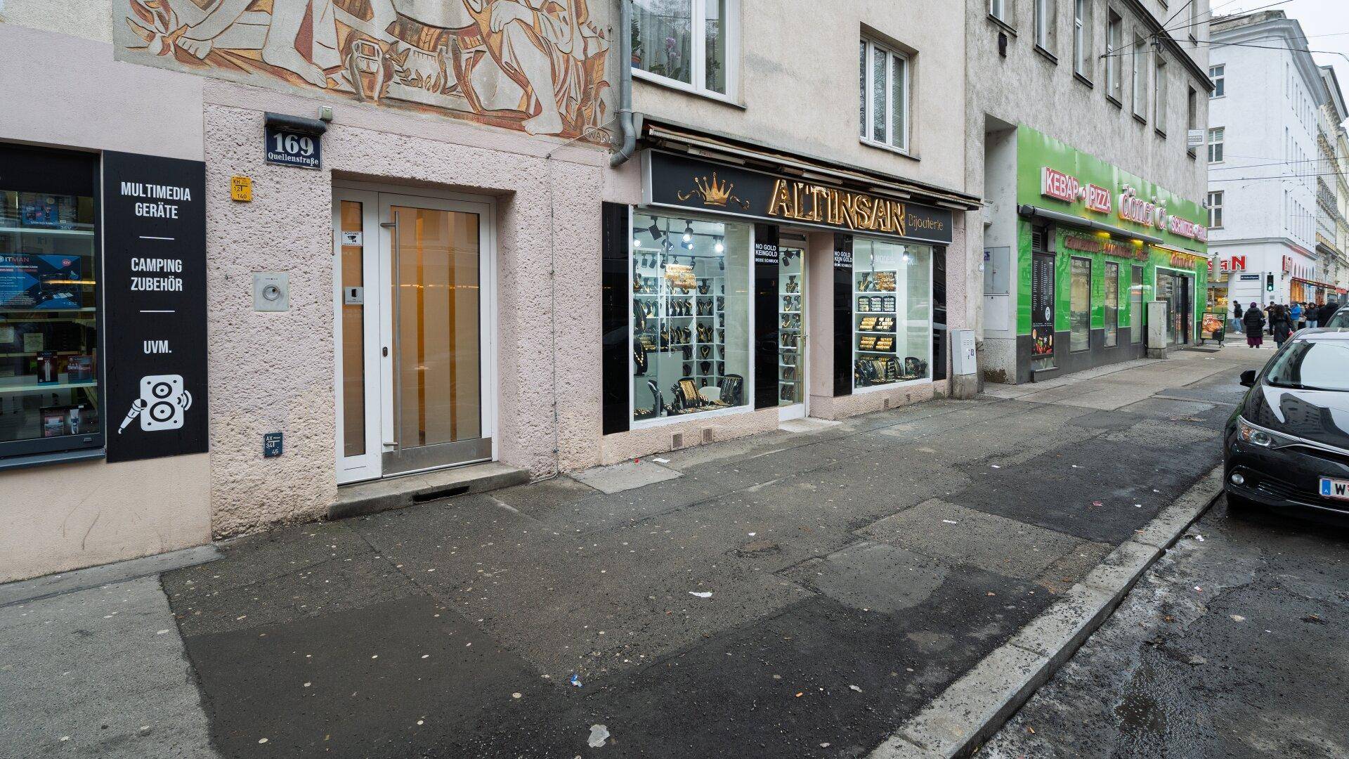 Straßenansicht eines Gebäudes mit Geschäften im Erdgeschoss und Wohnungen darüber in einer Stadt.