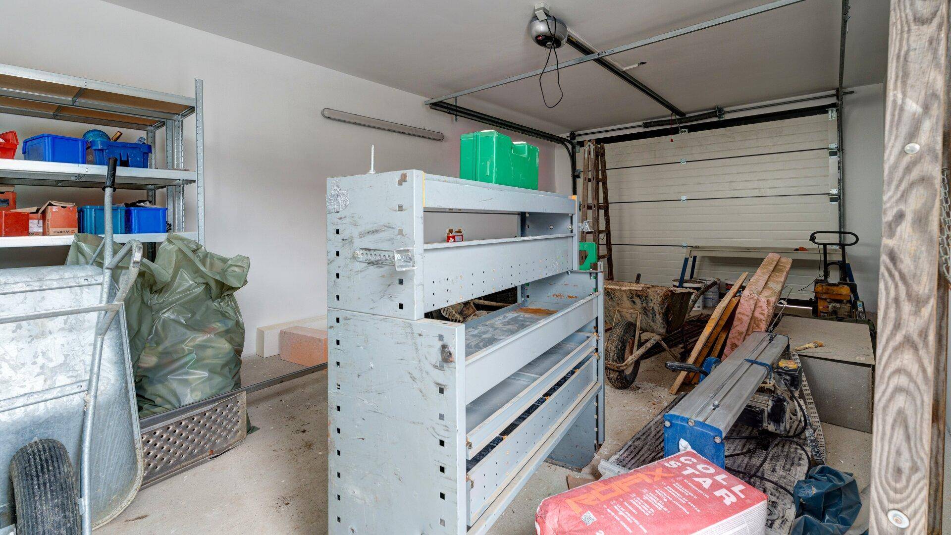 Geräumige Garage mit Regalen, Werkzeugen und einem Garagentor.