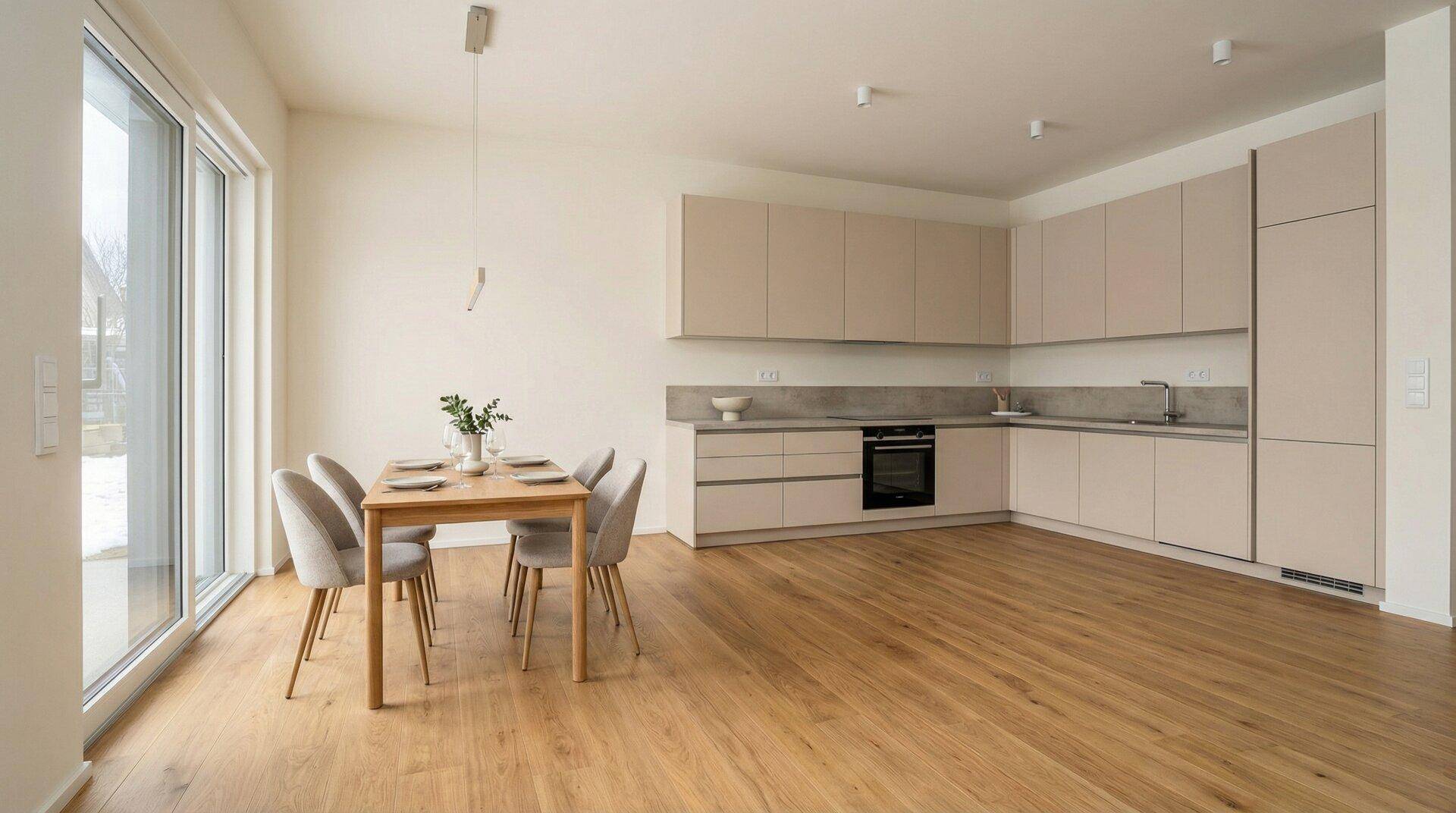 Moderne Einbauküche in hellem Beige mit Esstisch und Holzboden, offen gestaltet.