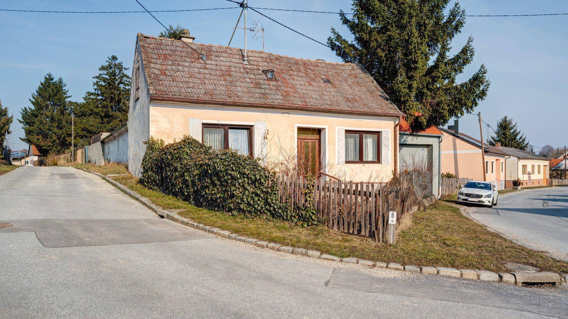 Einfaches Einfamilienhaus an einer ländlichen Straße mit altem Holzzaun.