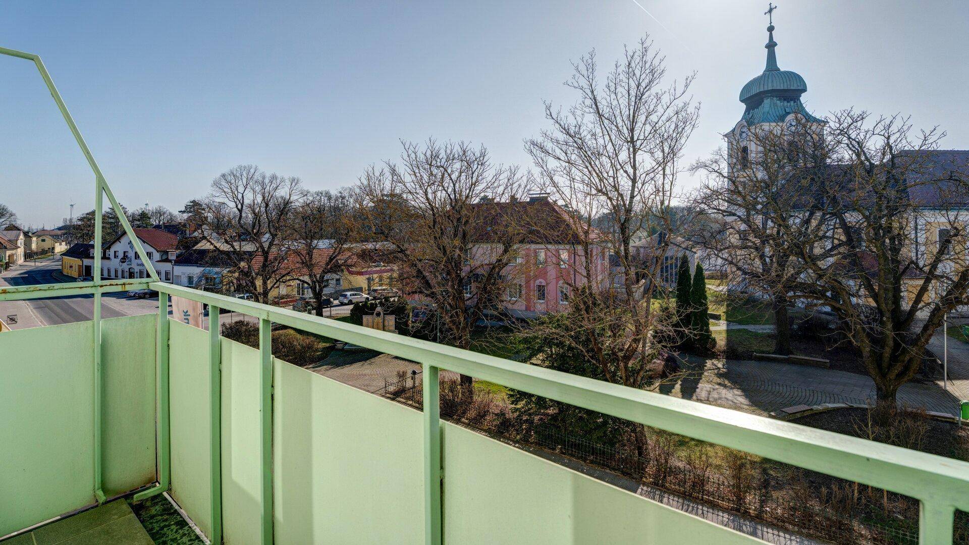 Balkon mit grüner Brüstung bietet Blick auf die Kirche und die umliegende Nachbarschaft.