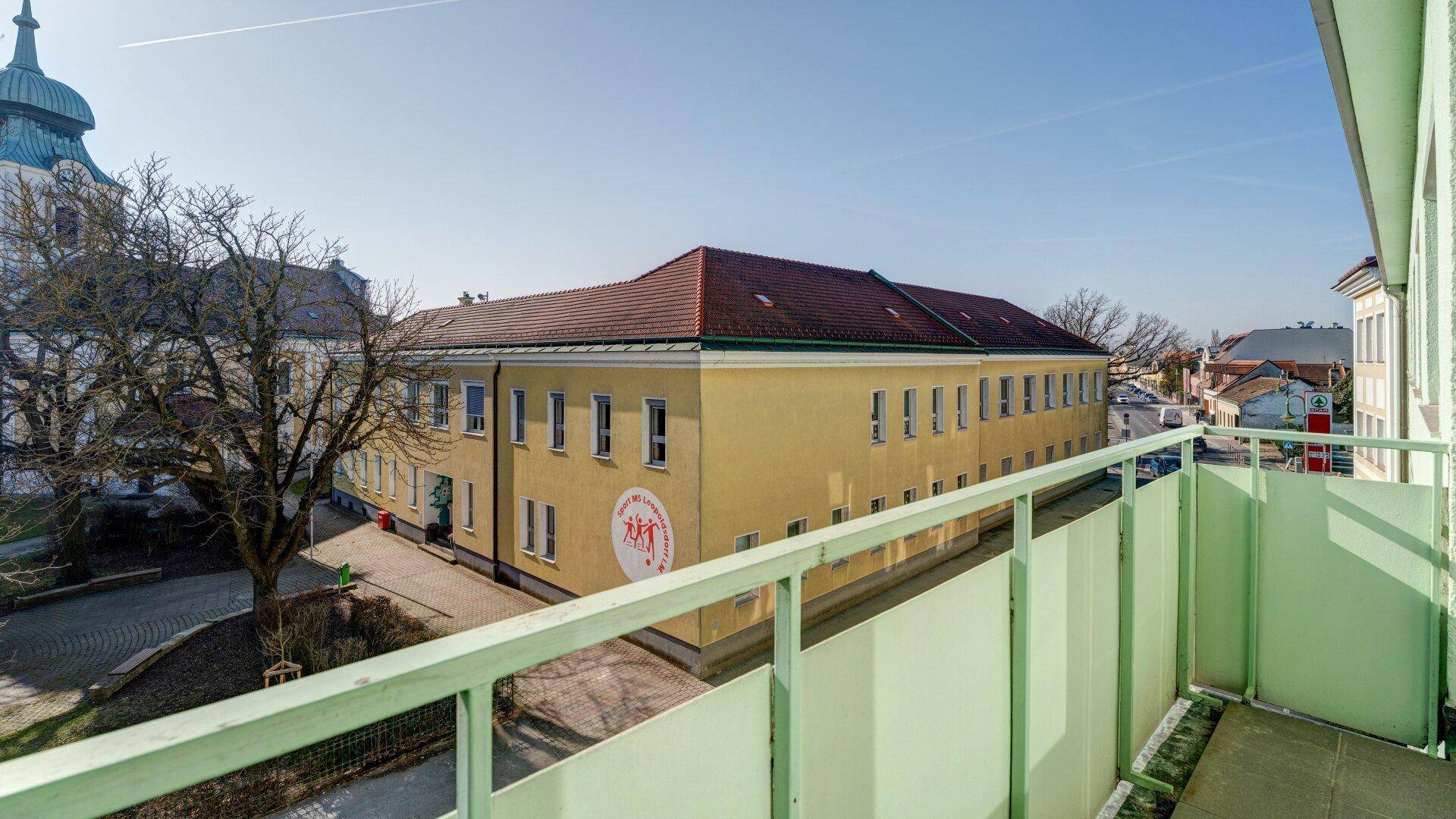 Balkon mit Blick auf ein gelbes Gebäude und die weitere Umgebung unter klarem Himmel.