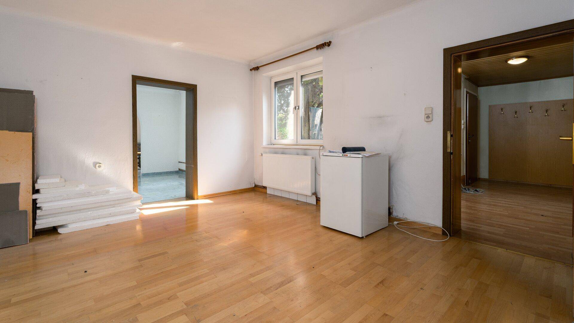 Geräumiges Zimmer mit Parkettboden und Fenster, bereit zur individuellen Gestaltung und Nutzung.