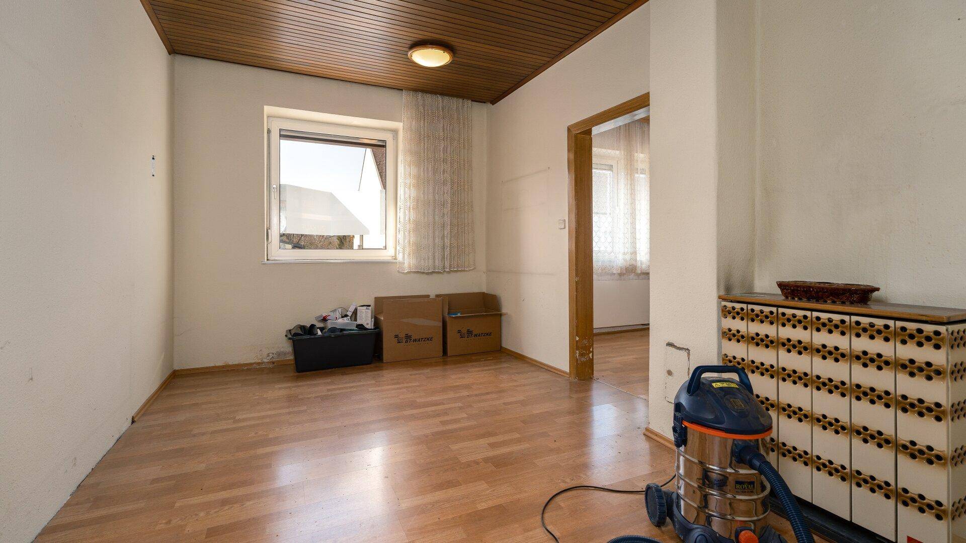 Zimmer mit Holzdecke und Parkettboden, ausgestattet mit einem Fenster für Tageslicht.