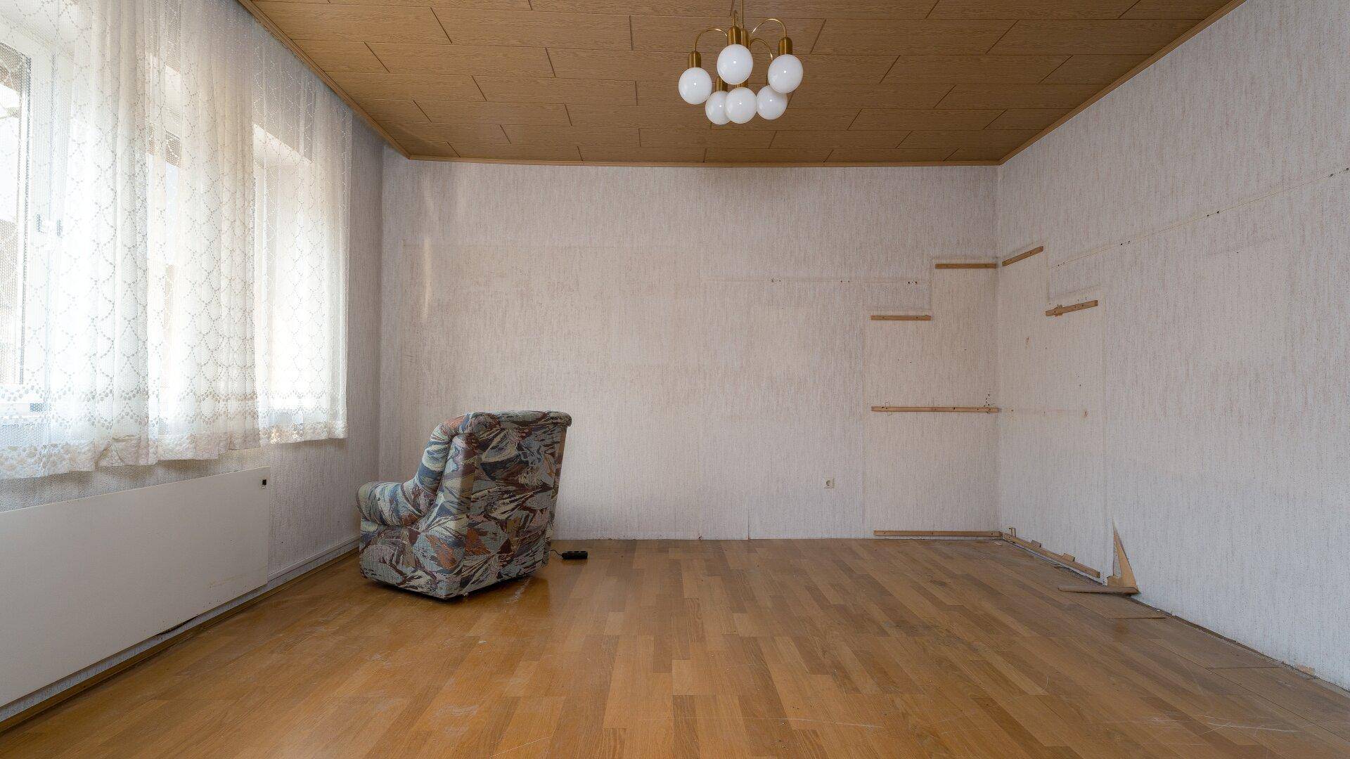 Geräumiges Zimmer mit Holzdecke und Parkettboden, bereit für eine umfassende Renovierung.