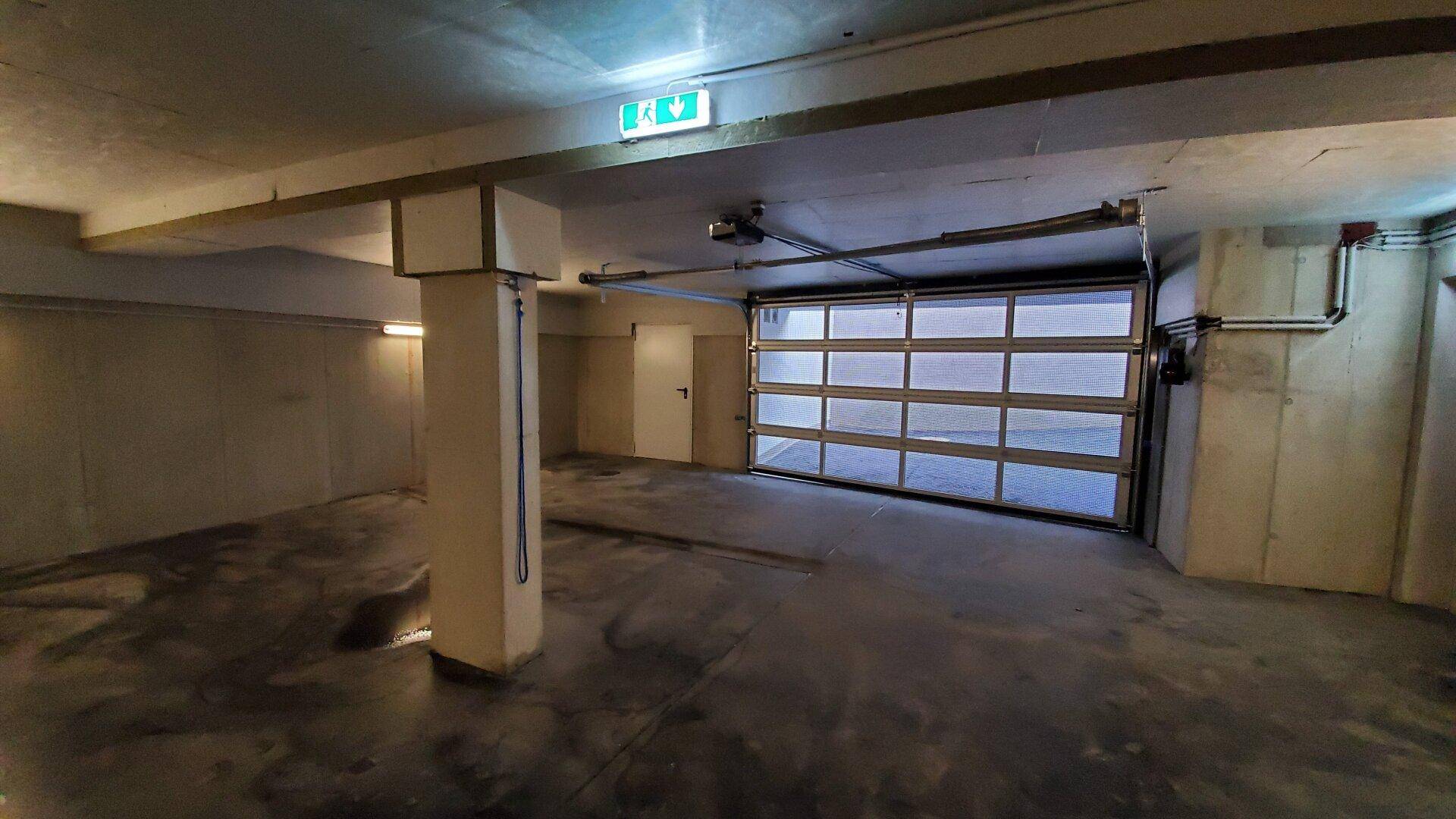 Tiefgarage mit Rolltor und Betonboden, ausreichend Platz für Fahrzeuge.