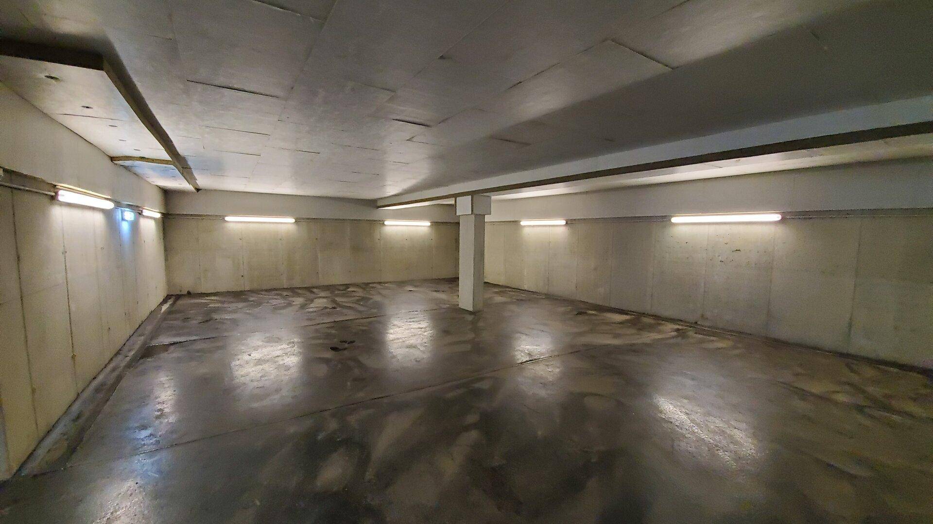 Geräumige Tiefgarage mit Betonwänden und -boden, gut beleuchtet.