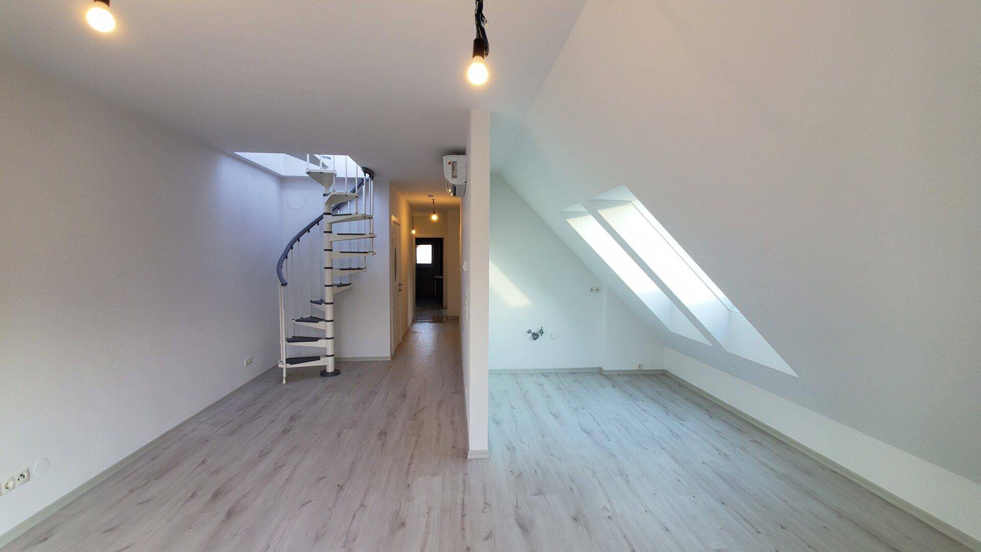 Heller Flur im Dachgeschoss mit Wendeltreppe und Dachfenstern, heller Laminatboden.