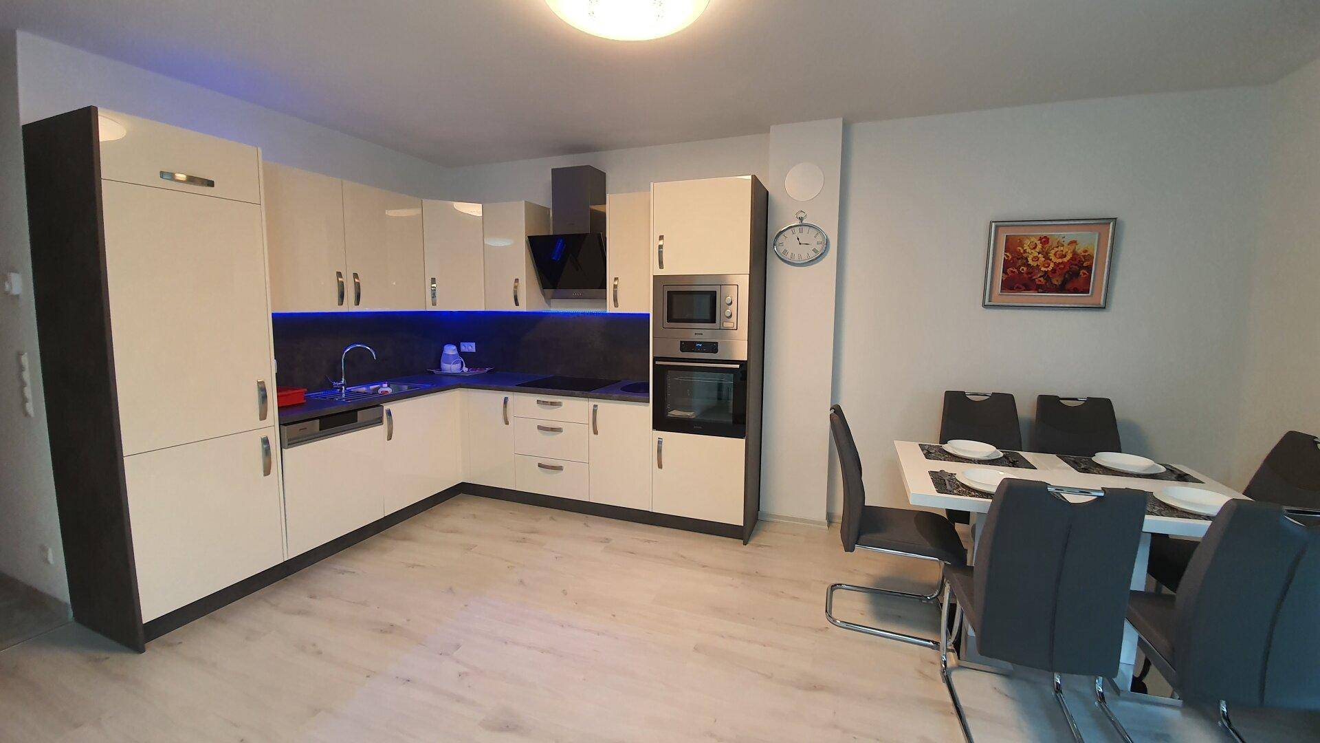 Moderne Einbauküche mit hellen Fronten, integrierten Geräten und Essbereich.