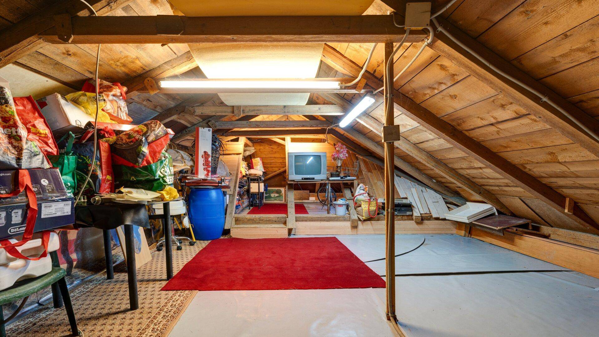Dachboden mit Holzbalken, Teppichboden und Stauraum.