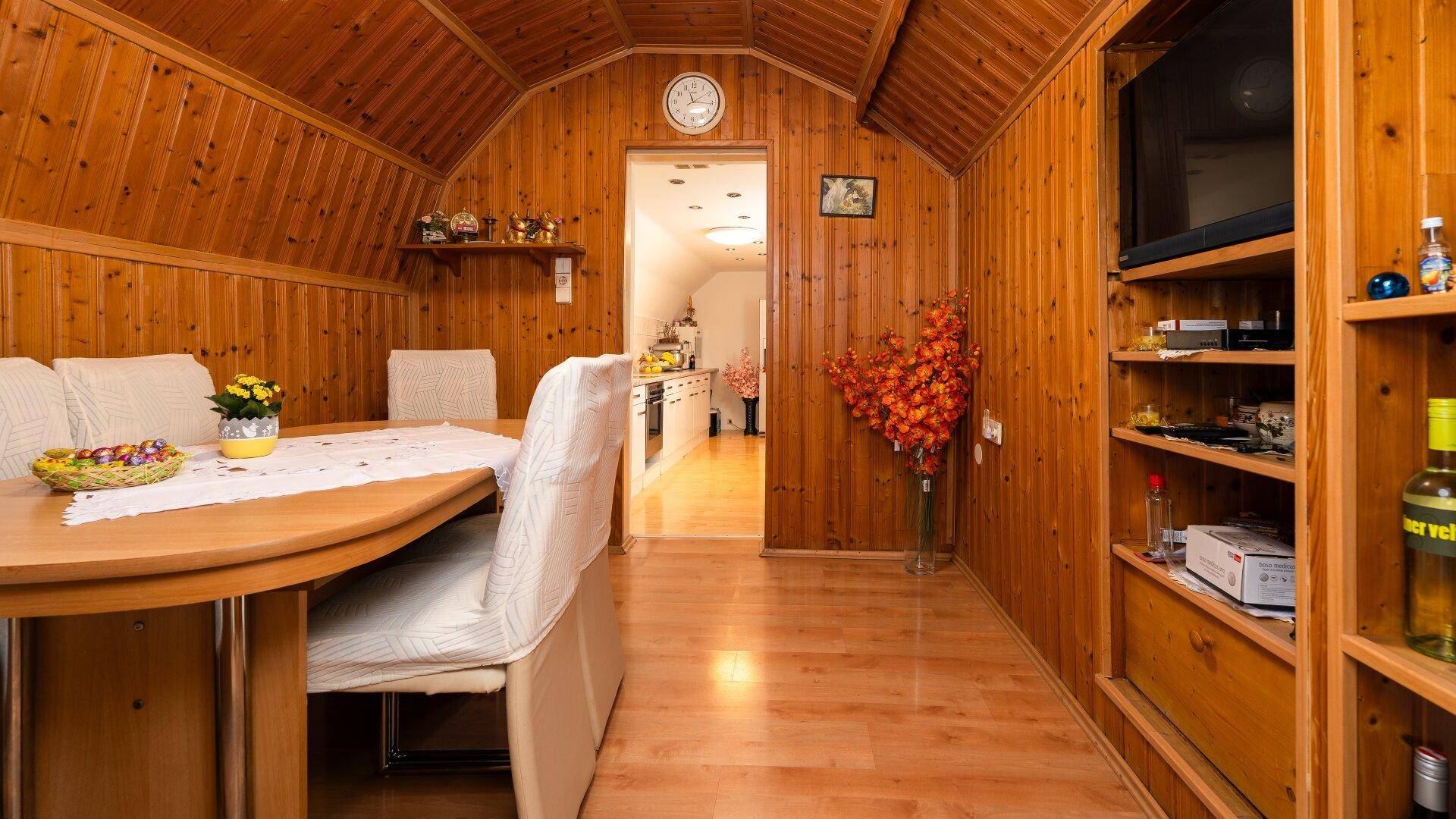 Gemütlicher Essbereich mit Holzvertäfelung, Holzboden und integriertem Regal.