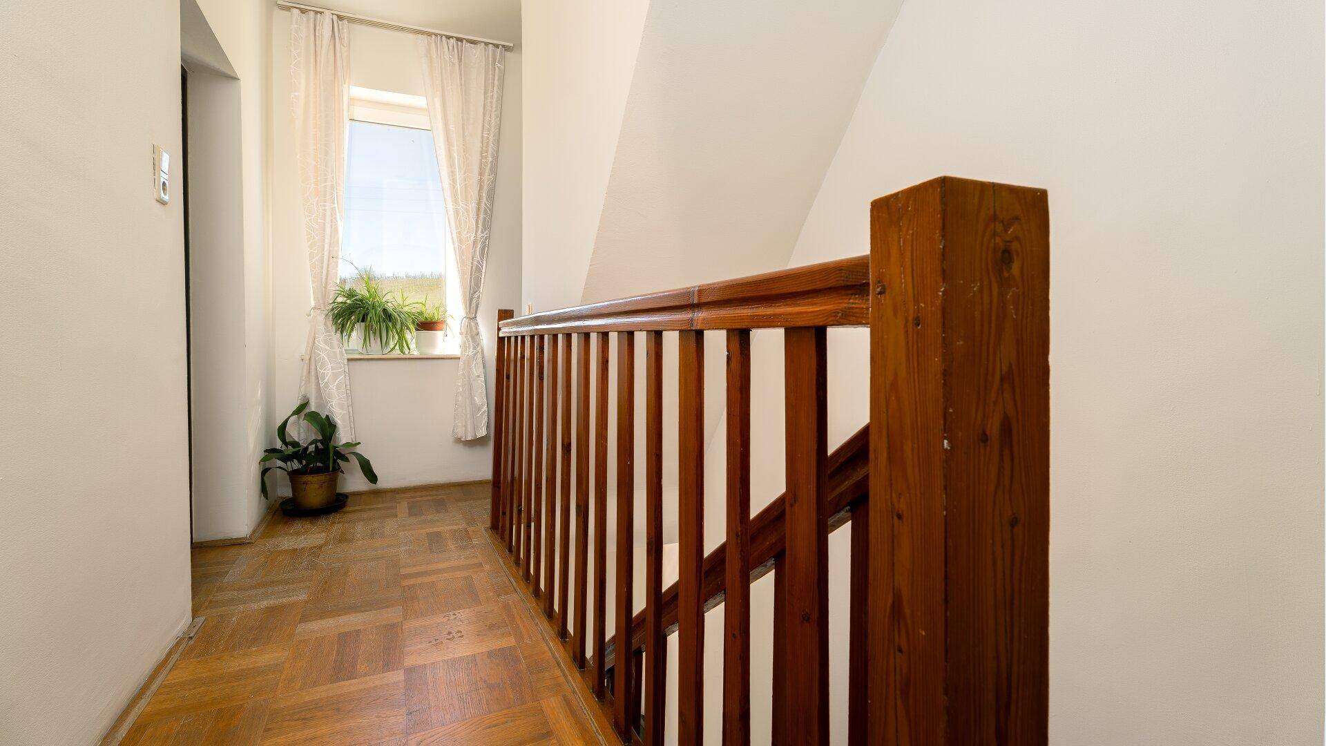 Heller Flur im Obergeschoss mit Holzgeländer und Parkettboden.