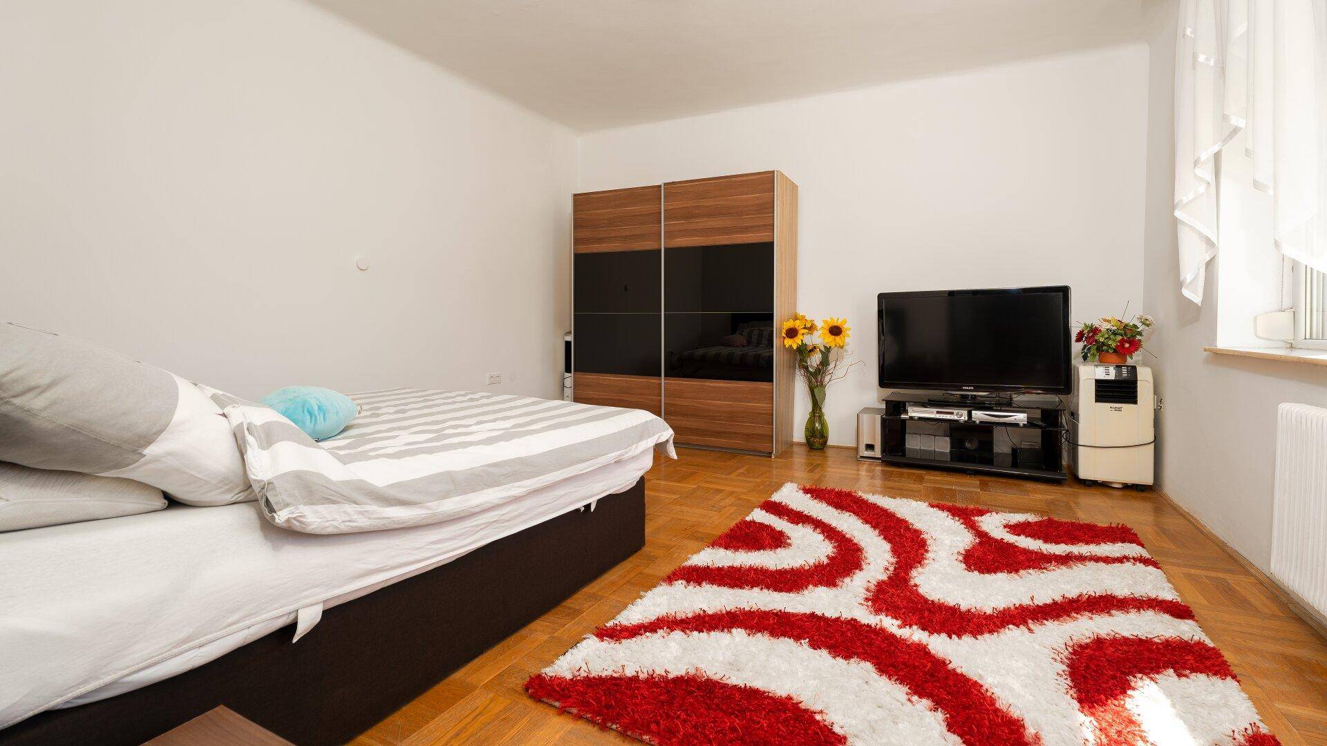 Schlafzimmer mit Doppelbett, Kleiderschrank und Parkettboden.