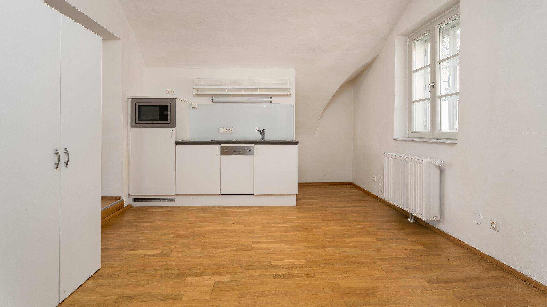 Funktionale Küchenzeile mit Spüle und Geschirrspüler in einem hellen Raum mit Parkettboden.