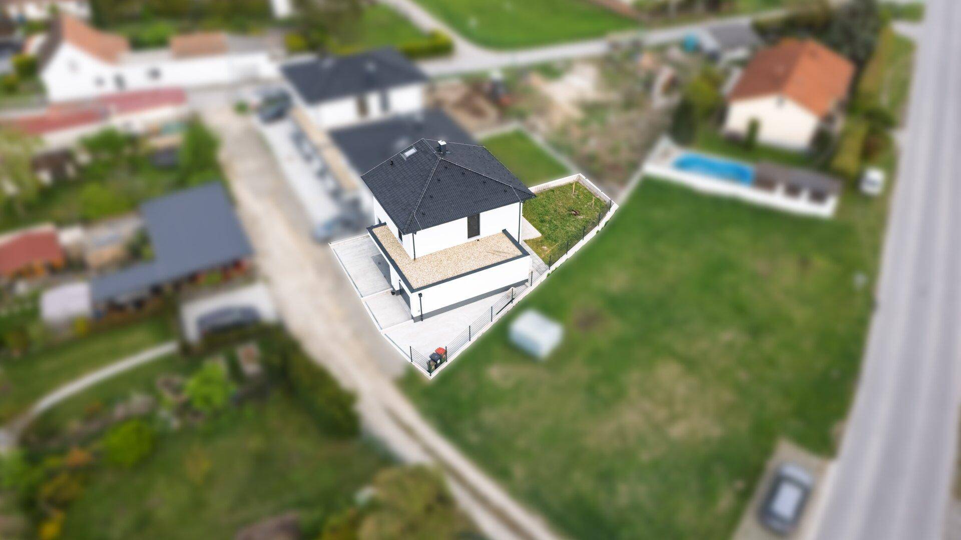 Luftaufnahme des Hauses mit Garten, Dach und umliegenden Grundstücken.