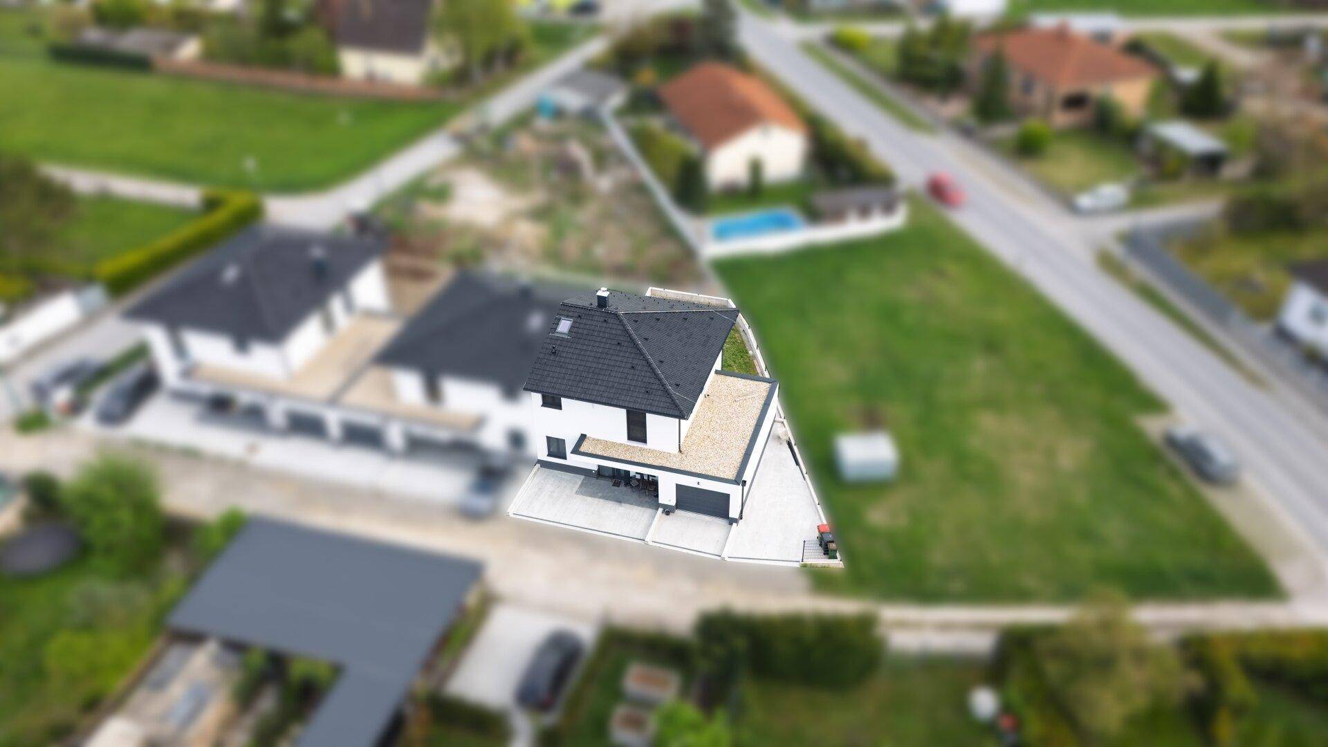 Luftaufnahme des Hauses mit Garage, Garten und der umgebenden Bebauung.