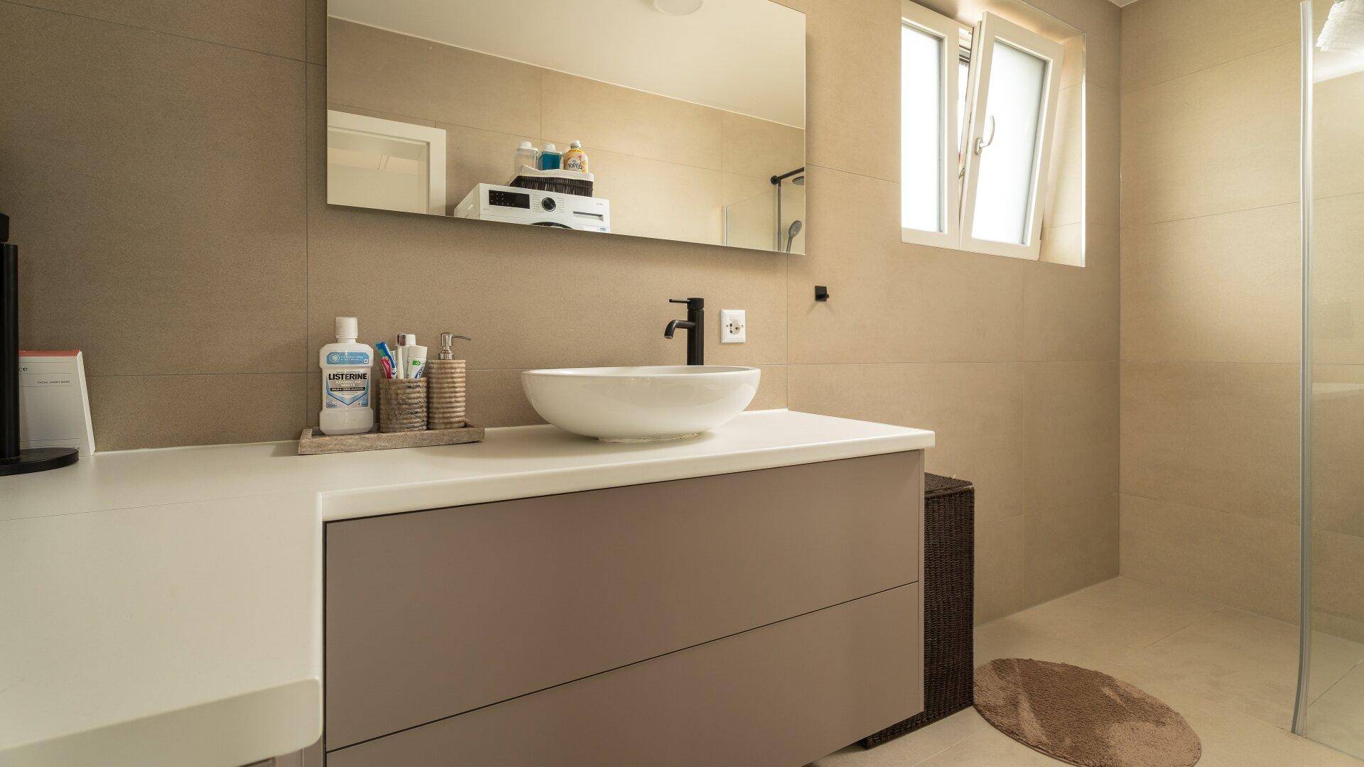Modernes Badezimmer mit großem Waschtisch, Spiegel und Fenster.