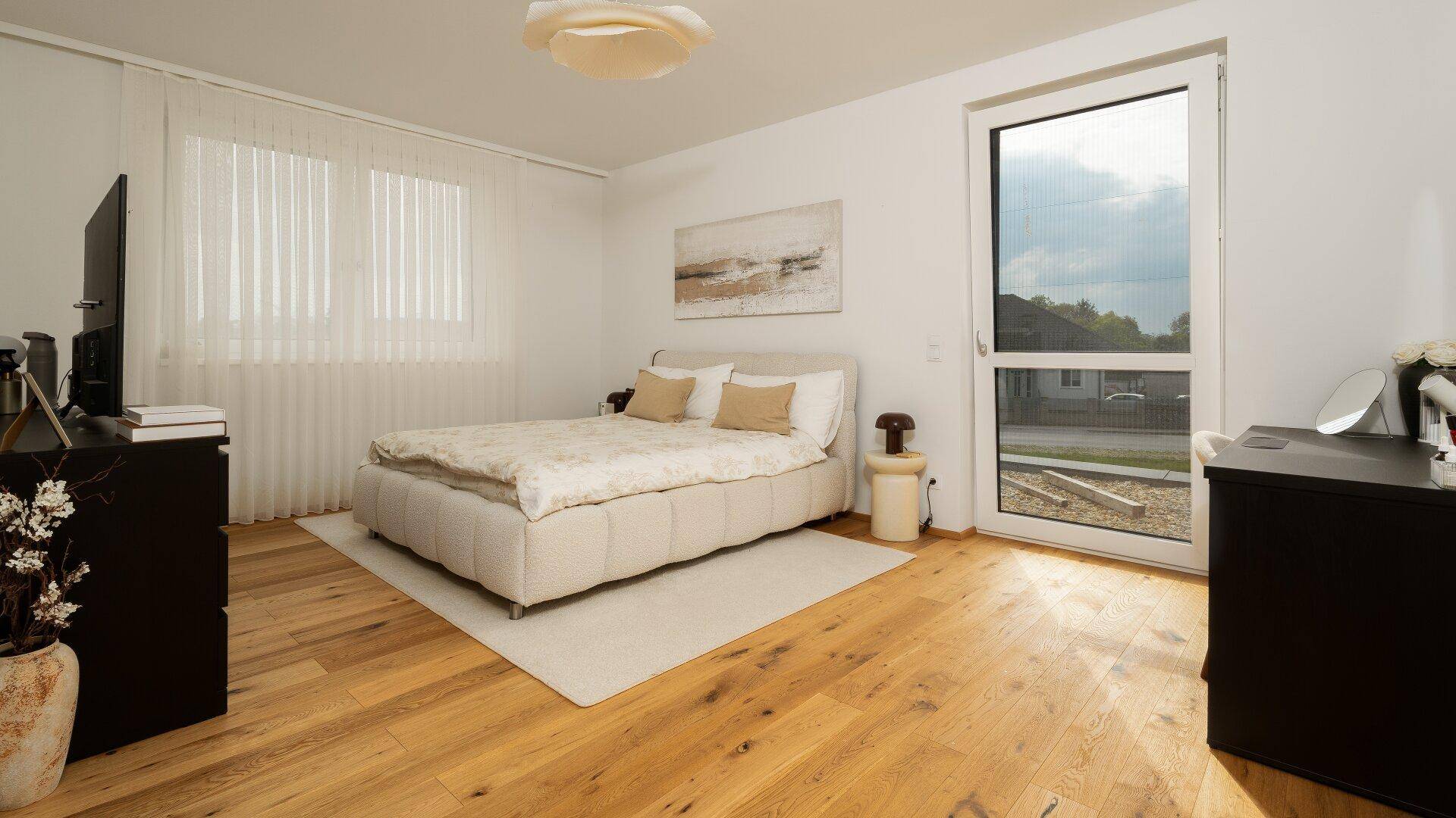 Helles Schlafzimmer mit Holzboden, Doppelbett und Zugang zum Außenbereich.