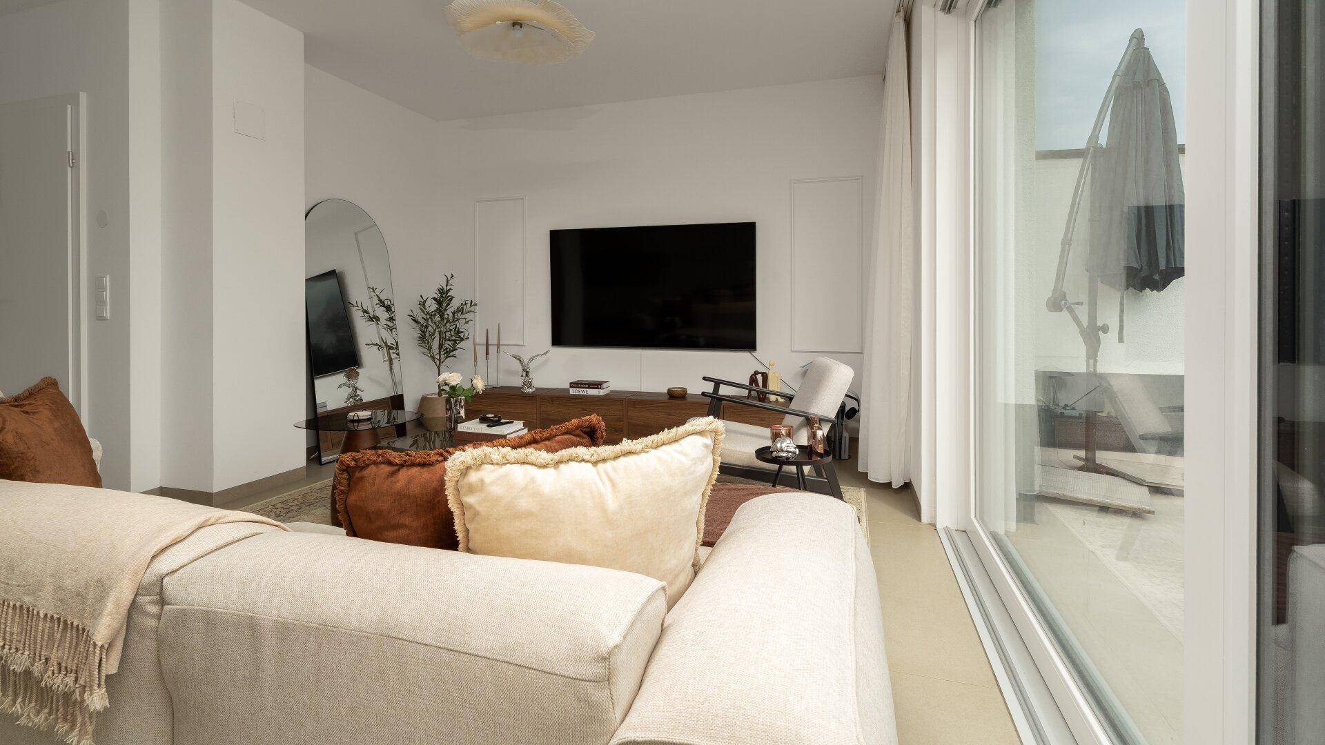 Gemütlicher Wohnbereich mit großem Sofa, Fernseher und Blick auf die Terrasse.