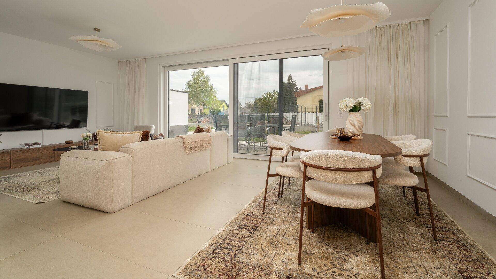Geräumiger Wohn-Essbereich mit großen Schiebetüren zur Terrasse und modernem Mobiliar.
